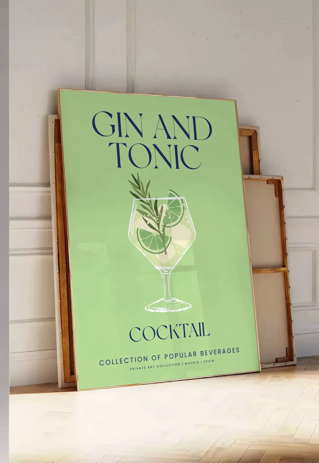 Tirage encadrable affiche cocktail Gin Tonic, posee au sol dans une entree lumineuse, contre un mur a panneaux blancs, a cote de chassis en bois empiles