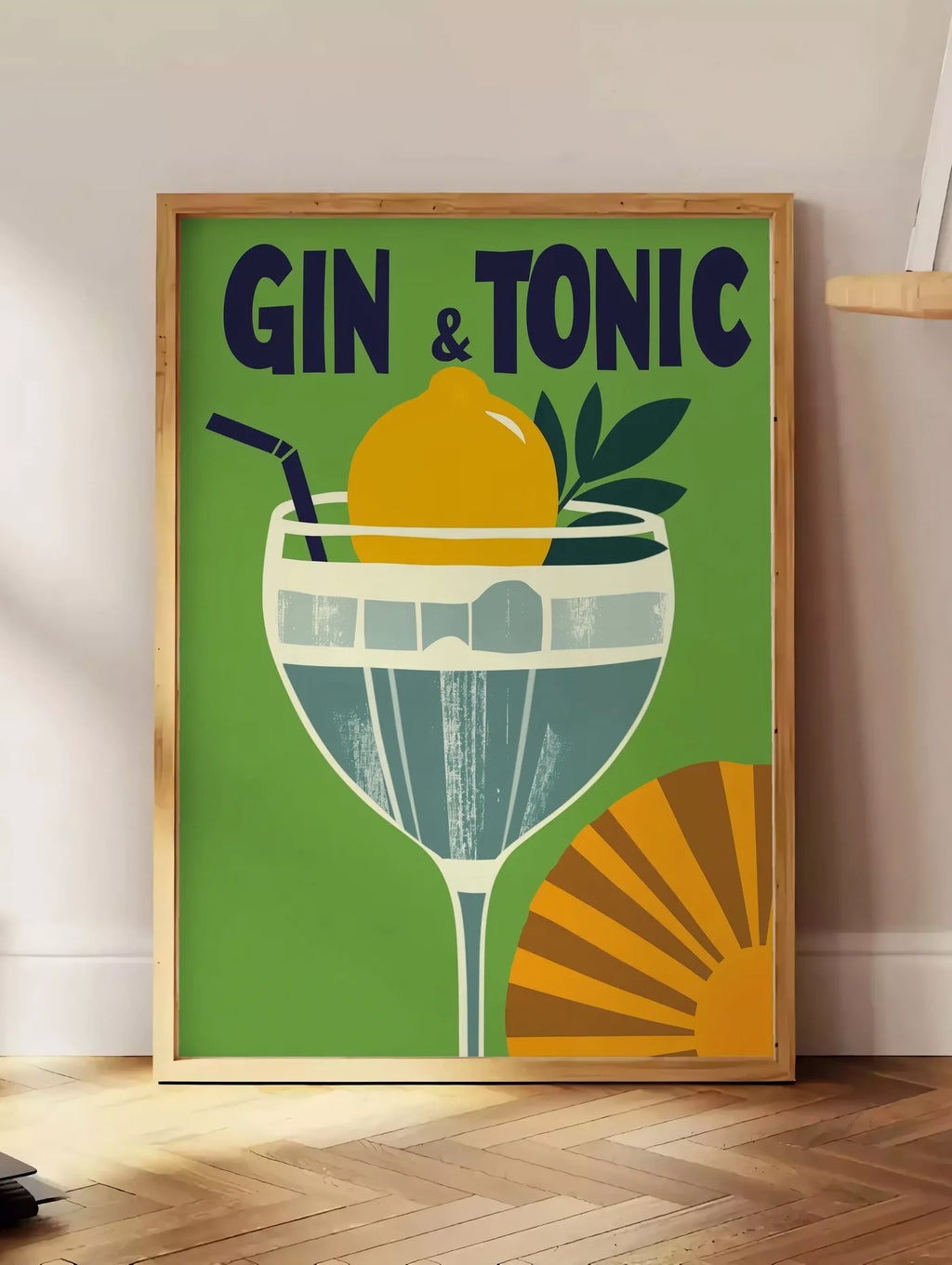 Estampe affiche cocktail Gin Tonic, posee au sol dans un coin salon, sur un parquet a chevrons, pres d'une table d'appoint en chene chargee de livres