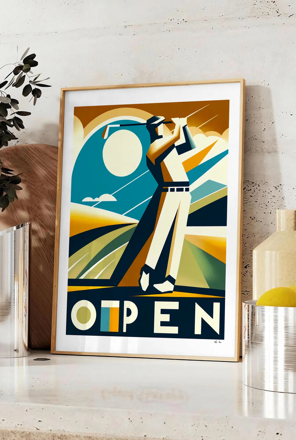 Affiche affiche Open golf Art Deco, posee sur un plan de travail de cuisine en pierre claire, entre une branche d'eucalyptus en vase et un bocal de citrons