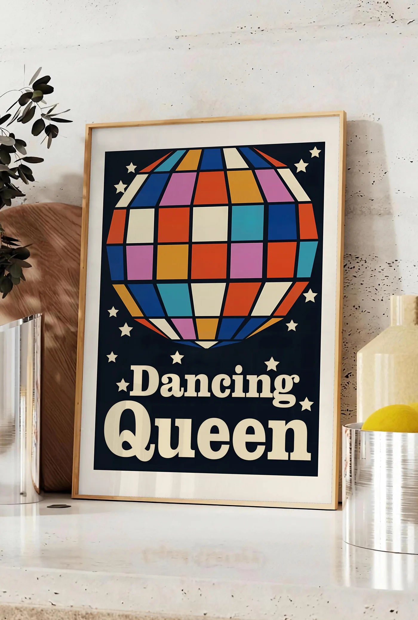 Affiche affiche vintage Dancing Queen, posee sur un plan de travail de cuisine en pierre claire, entre une branche d'eucalyptus en vase et un bocal de citrons