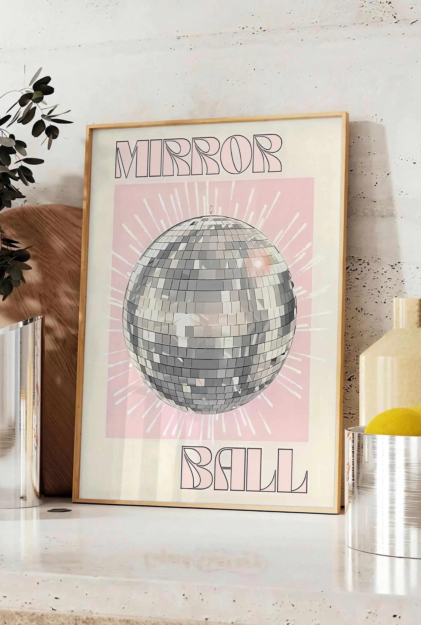 Affiche affiche vintage Mirror Ball, posee sur un plan de travail de cuisine en pierre claire, entre une branche d'eucalyptus en vase et un bocal de citrons