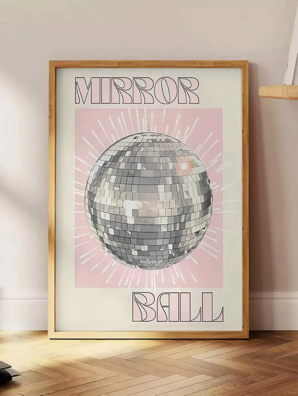 Estampe affiche vintage Mirror Ball, posee au sol dans un coin salon, sur un parquet a chevrons, pres d'une table d'appoint en chene chargee de livres