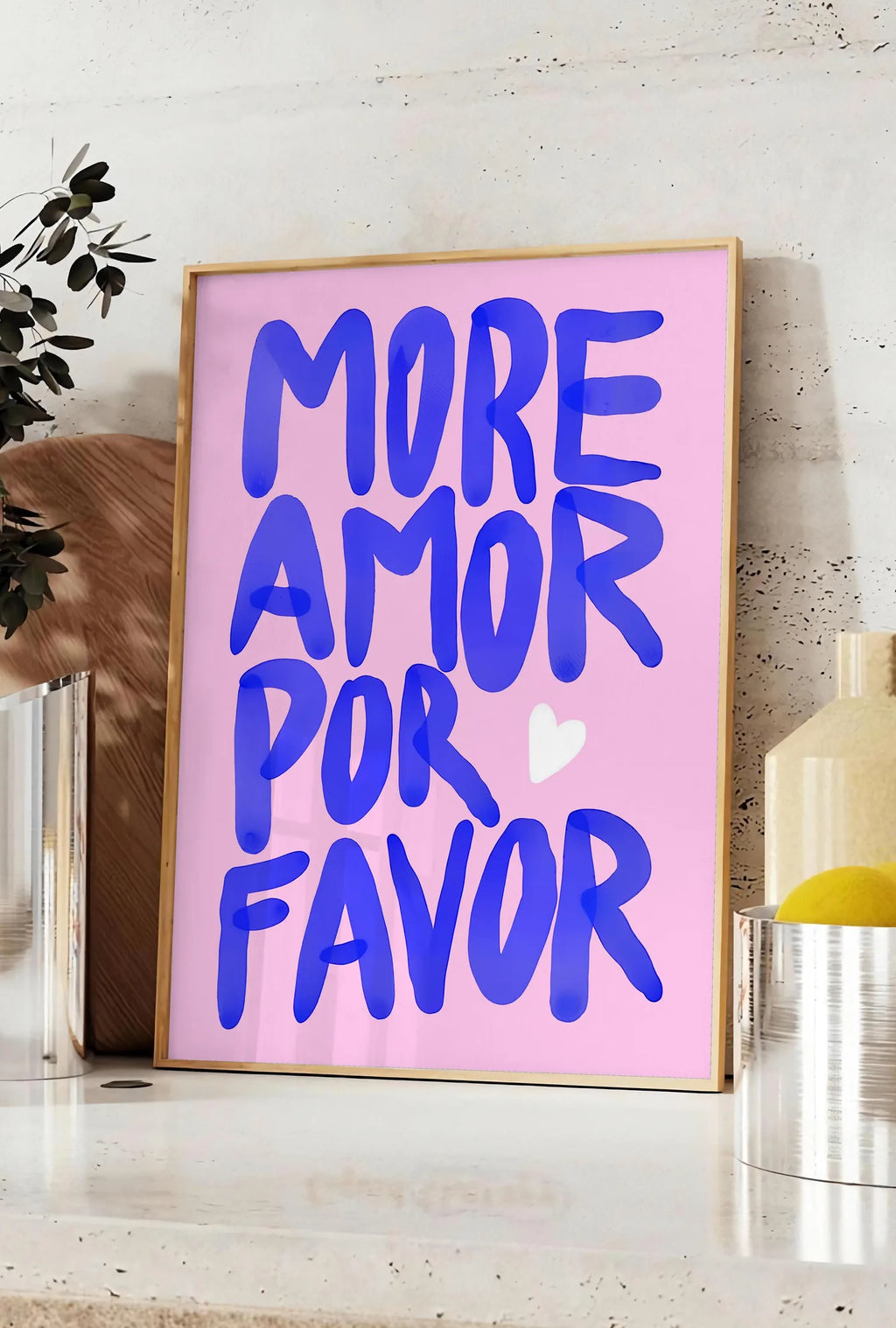 Affiche affiche vintage More Amor Por Favor, posee sur un plan de travail de cuisine en pierre claire, entre une branche d'eucalyptus en vase et un bocal de citrons