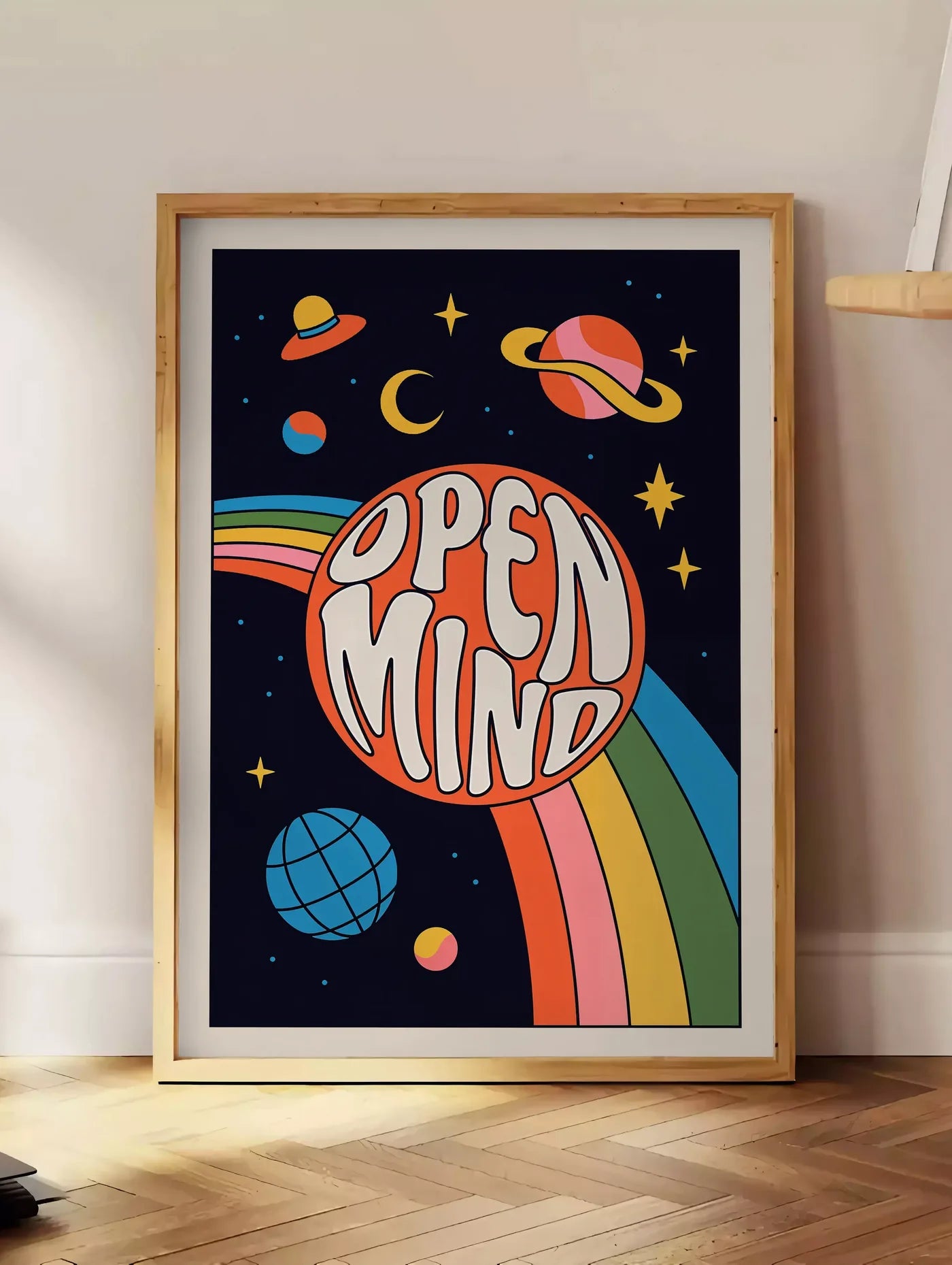 Estampe affiche vintage Open Mind, posee au sol dans un coin salon, sur un parquet a chevrons, pres d'une table d'appoint en chene chargee de livres