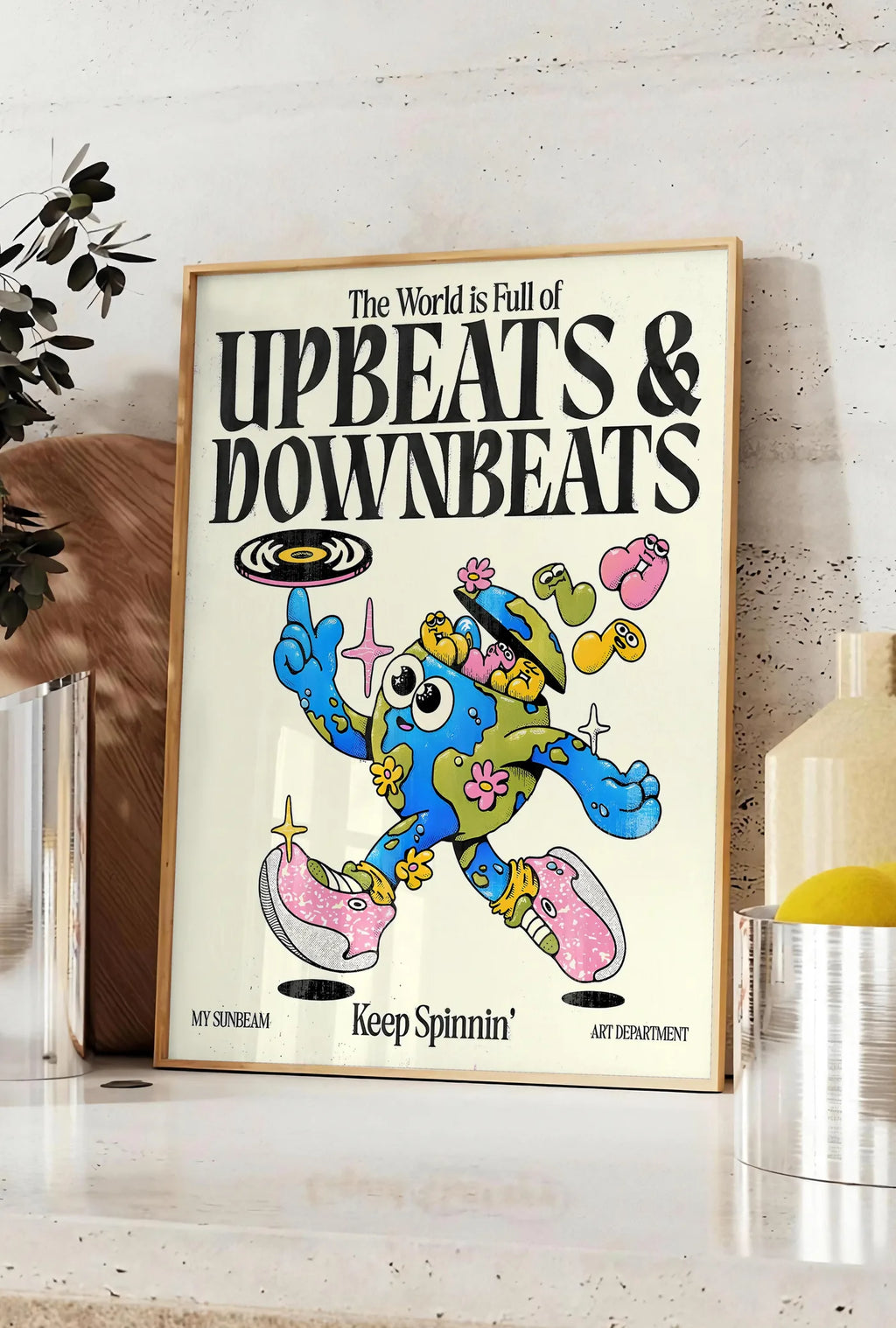 Affiche affiche vintage Upbeats and Downbeats, posee sur un plan de travail de cuisine en pierre claire, entre une branche d'eucalyptus en vase et un bocal de citrons