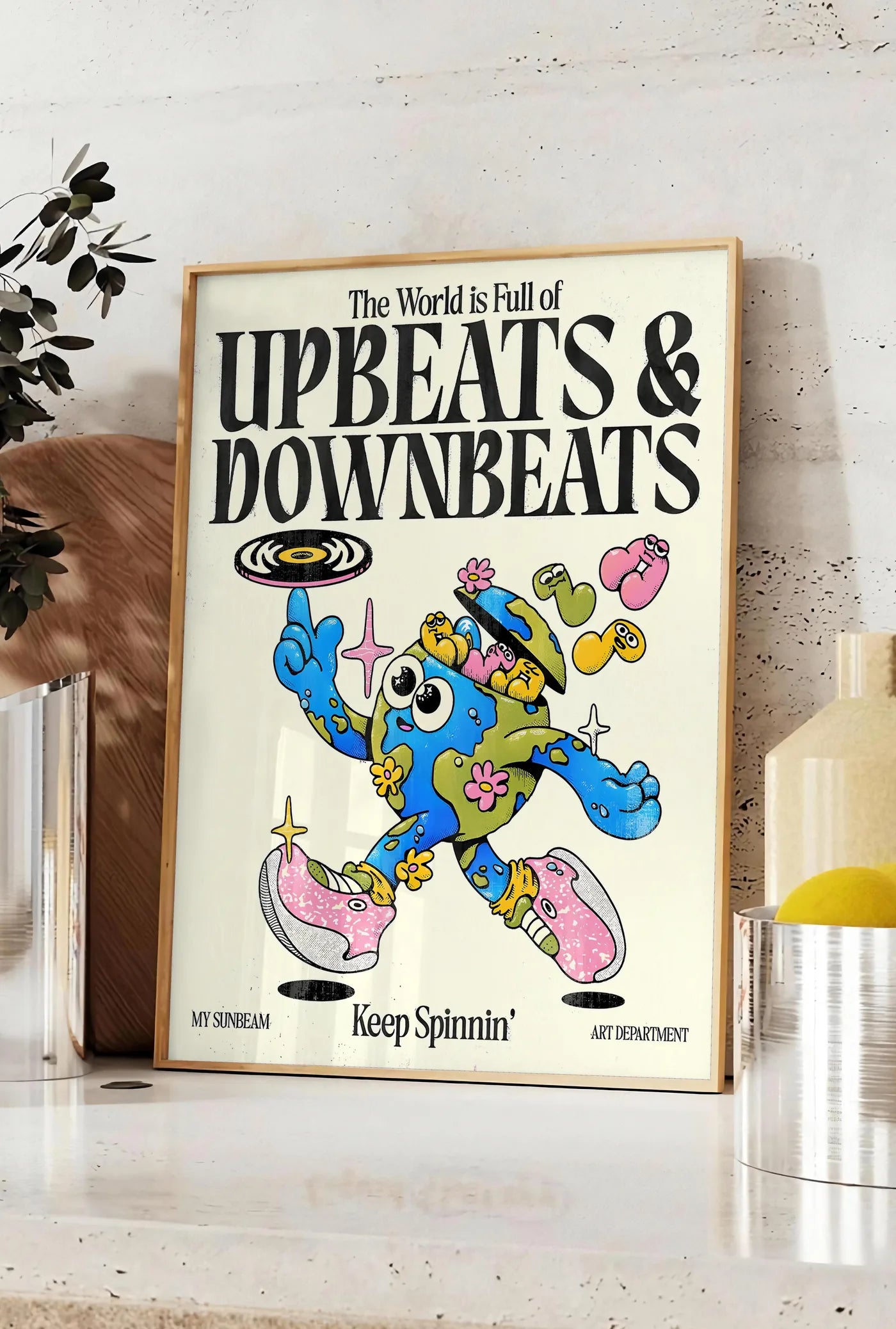 Affiche affiche vintage Upbeats and Downbeats, posee sur un plan de travail de cuisine en pierre claire, entre une branche d'eucalyptus en vase et un bocal de citrons