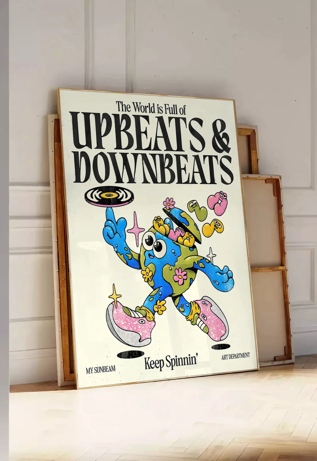 Tirage encadrable affiche vintage Upbeats and Downbeats, posee au sol dans une entree lumineuse, contre un mur a panneaux blancs, a cote de chassis en bois empiles