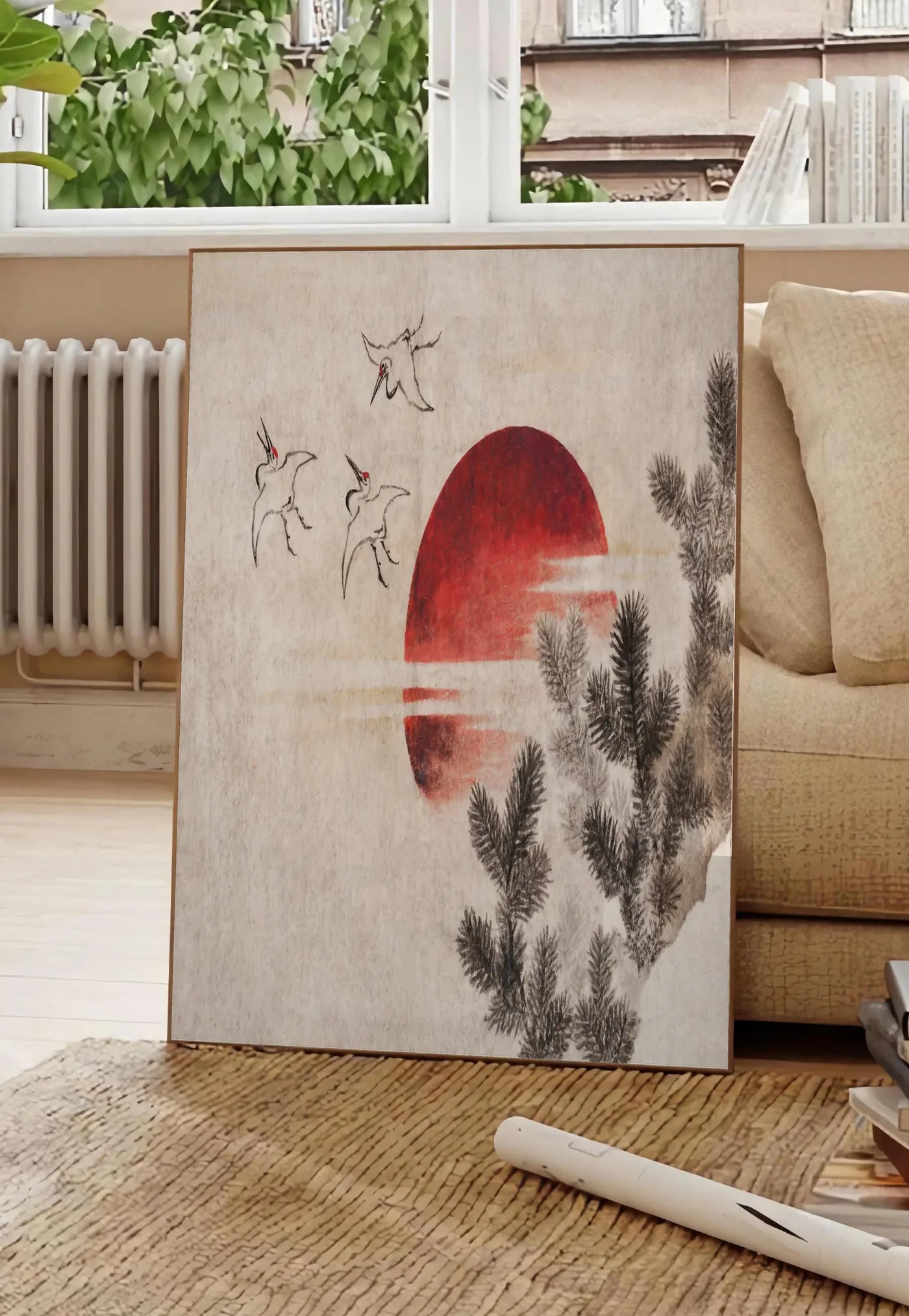 Poster affiche grues et soleil rouge art japonais, posee au sol dans un salon parisien, devant une grande fenetre donnant sur un immeuble haussmannien, entre un ficus et un canape creme