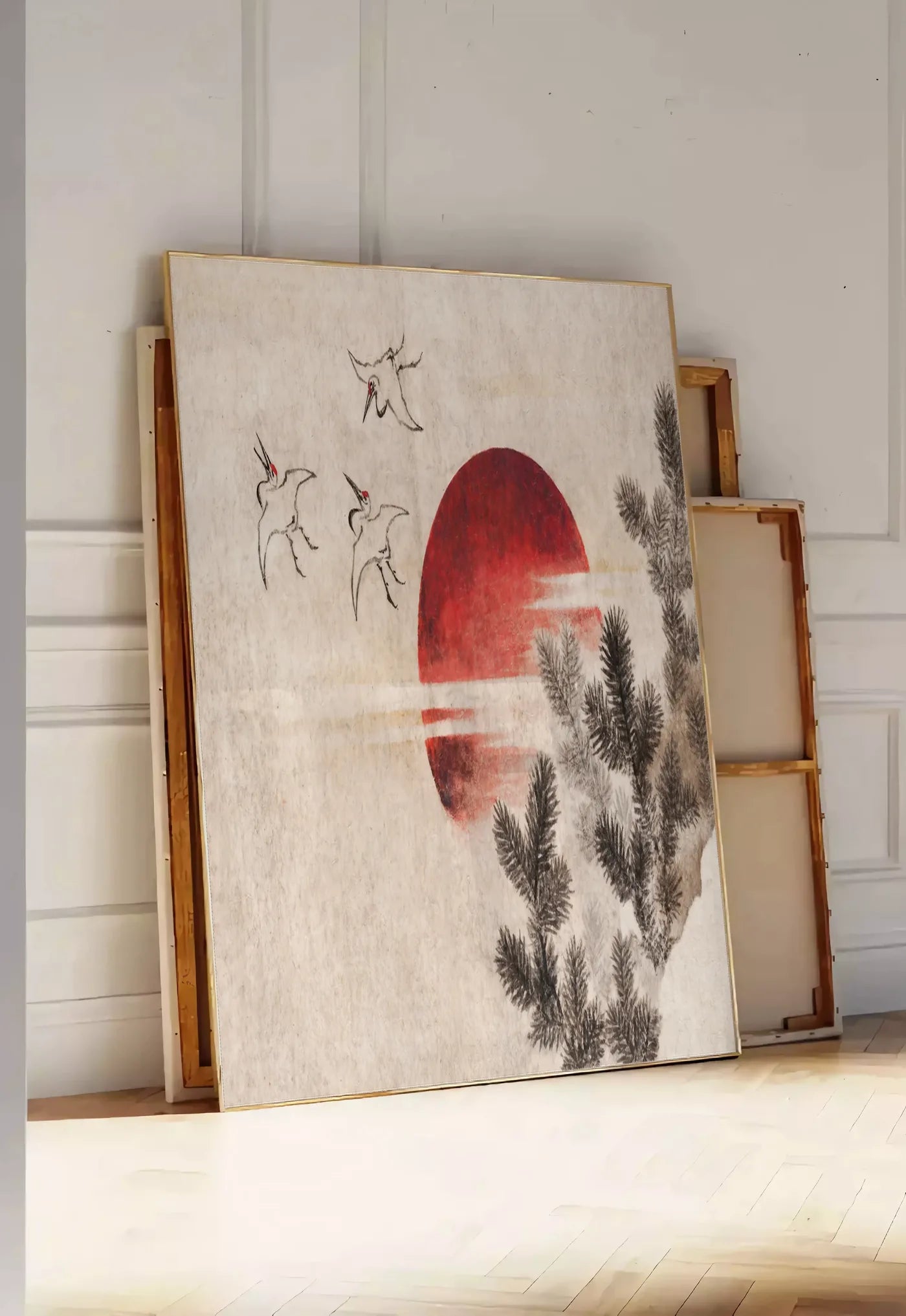 Tirage encadrable affiche grues et soleil rouge art japonais, posee au sol dans une entree lumineuse, contre un mur a panneaux blancs, a cote de chassis en bois empiles