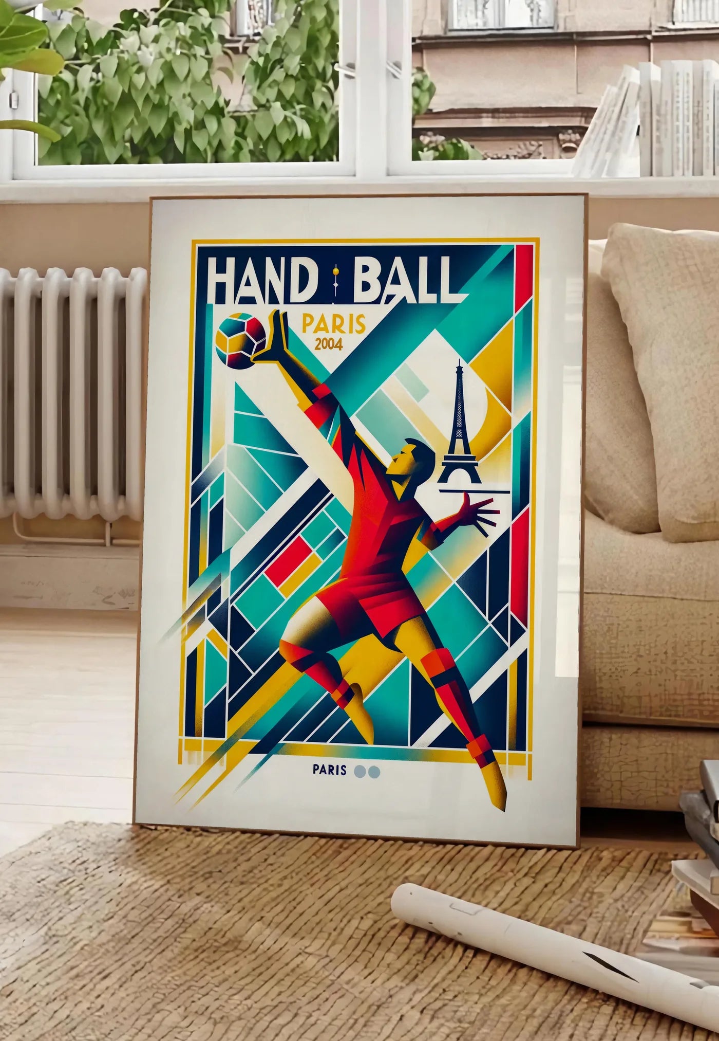 Poster stylisé joueur de handball en saut, posee au sol dans un salon parisien, devant une grande fenetre donnant sur un immeuble haussmannien, entre un ficus et un canape creme