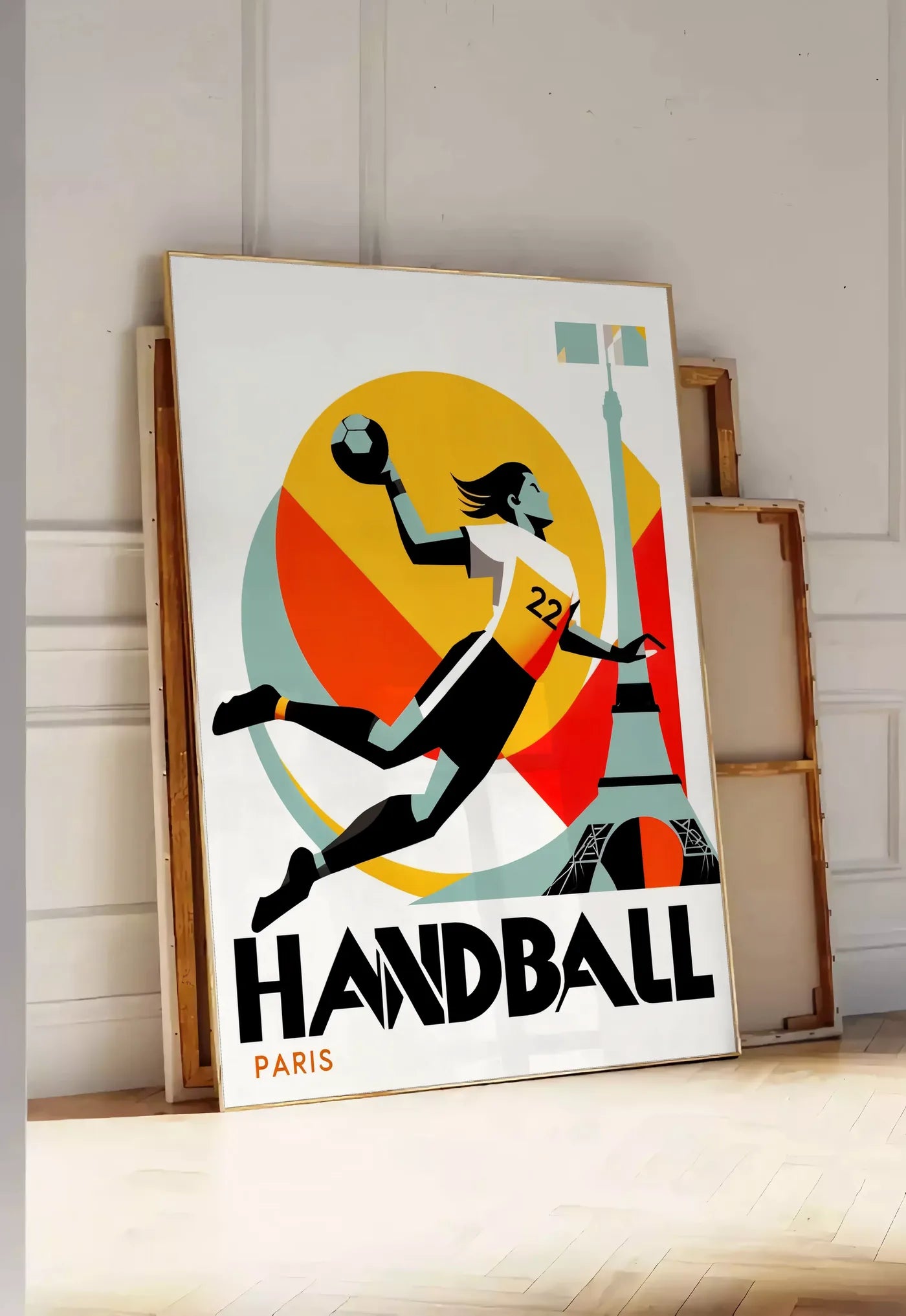 Tirage encadrable affiche handball Paris, posee au sol dans une entree lumineuse, contre un mur a panneaux blancs, a cote de chassis en bois empiles
