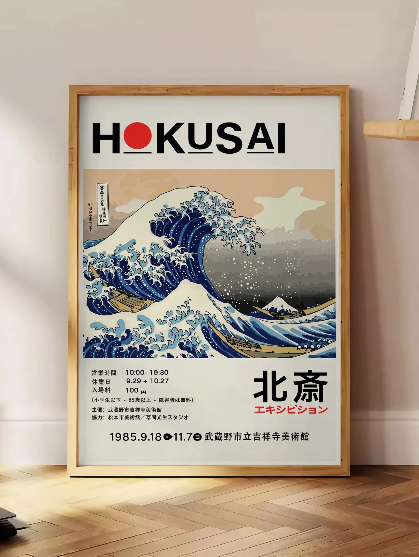 Estampe affiche Hokusai grande vague de Kanagawa, posee au sol dans un coin salon, sur un parquet a chevrons, pres d'une table d'appoint en chene chargee de livres