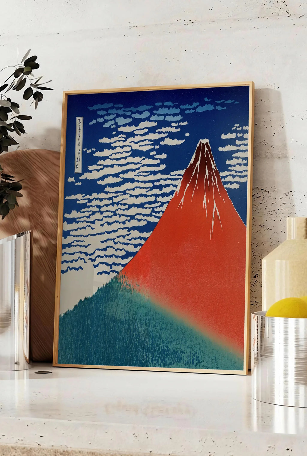 Affiche affiche mont Fuji rouge de Hokusai art japonais, posee sur un plan de travail de cuisine en pierre claire, entre une branche d'eucalyptus en vase et un bocal de citrons