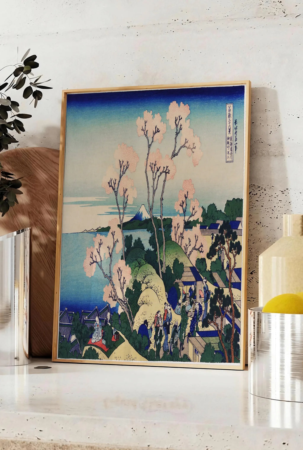Affiche affiche cerisiers de Goten-yama de Hokusai art japonais, posee sur un plan de travail de cuisine en pierre claire, entre une branche d'eucalyptus en vase et un bocal de citrons