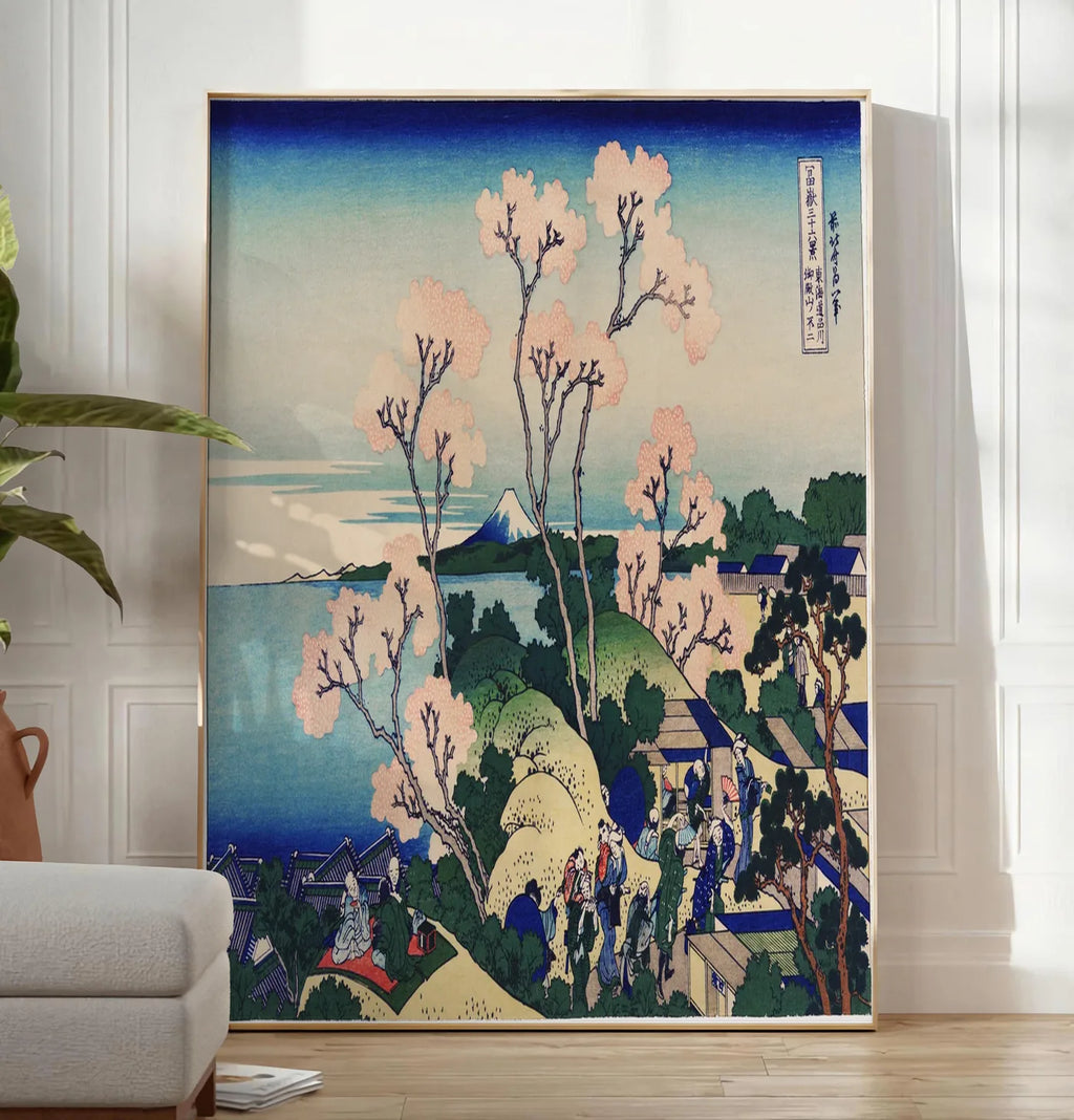 Reproduction affiche cerisiers de Goten-yama de Hokusai art japonais, posee au sol dans un salon minimaliste clair, a cote d'un canape beige et d'une plante verte, sur un parquet clair