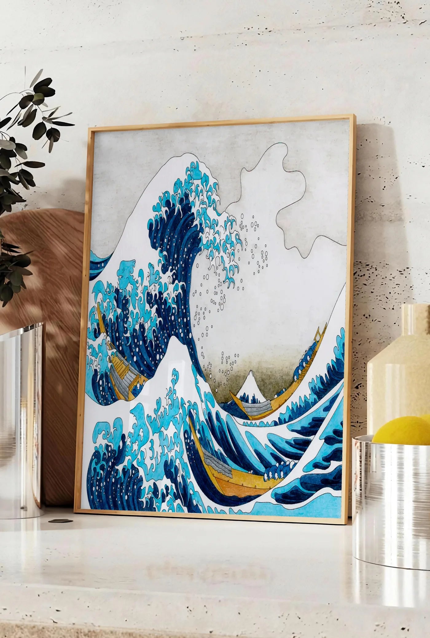 Affiche affiche Hokusai grande vague coloree, posee sur un plan de travail de cuisine en pierre claire, entre une branche d'eucalyptus en vase et un bocal de citrons