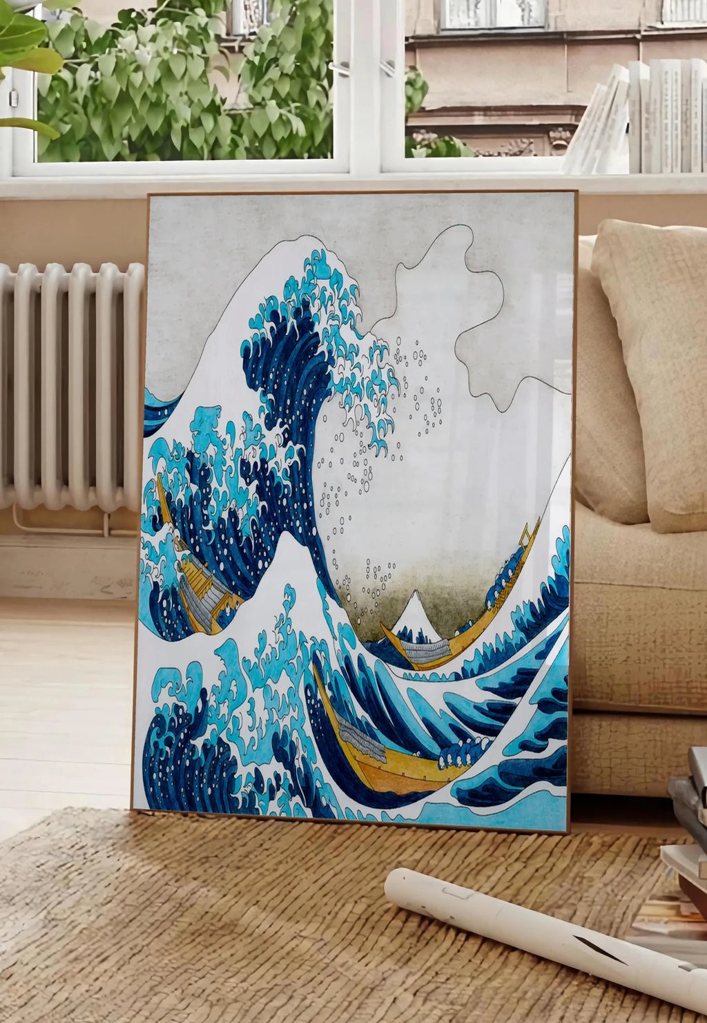 Poster affiche Hokusai grande vague coloree, posee au sol dans un salon parisien, devant une grande fenetre donnant sur un immeuble haussmannien, entre un ficus et un canape creme