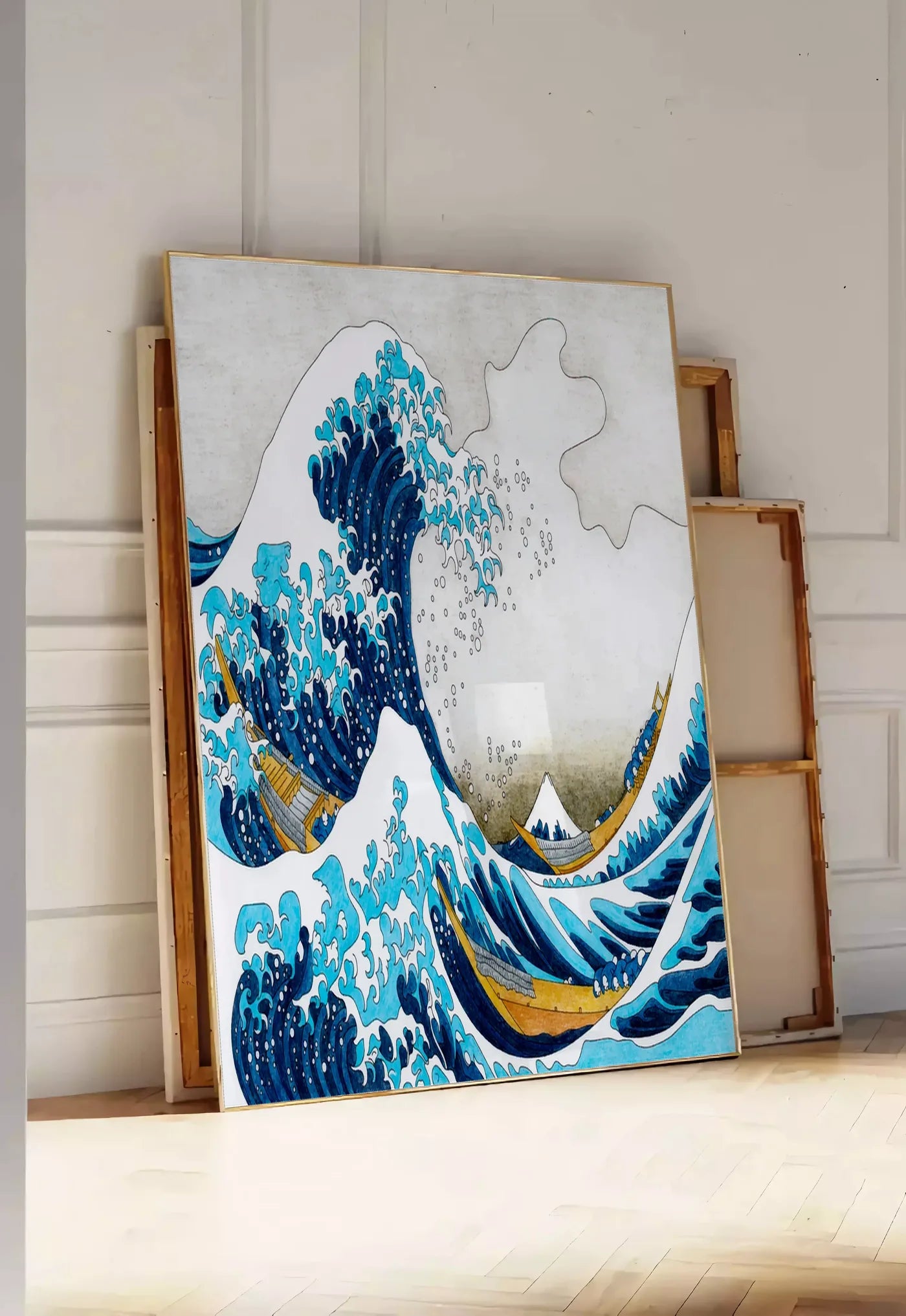 Tirage encadrable affiche Hokusai grande vague coloree, posee au sol dans une entree lumineuse, contre un mur a panneaux blancs, a cote de chassis en bois empiles