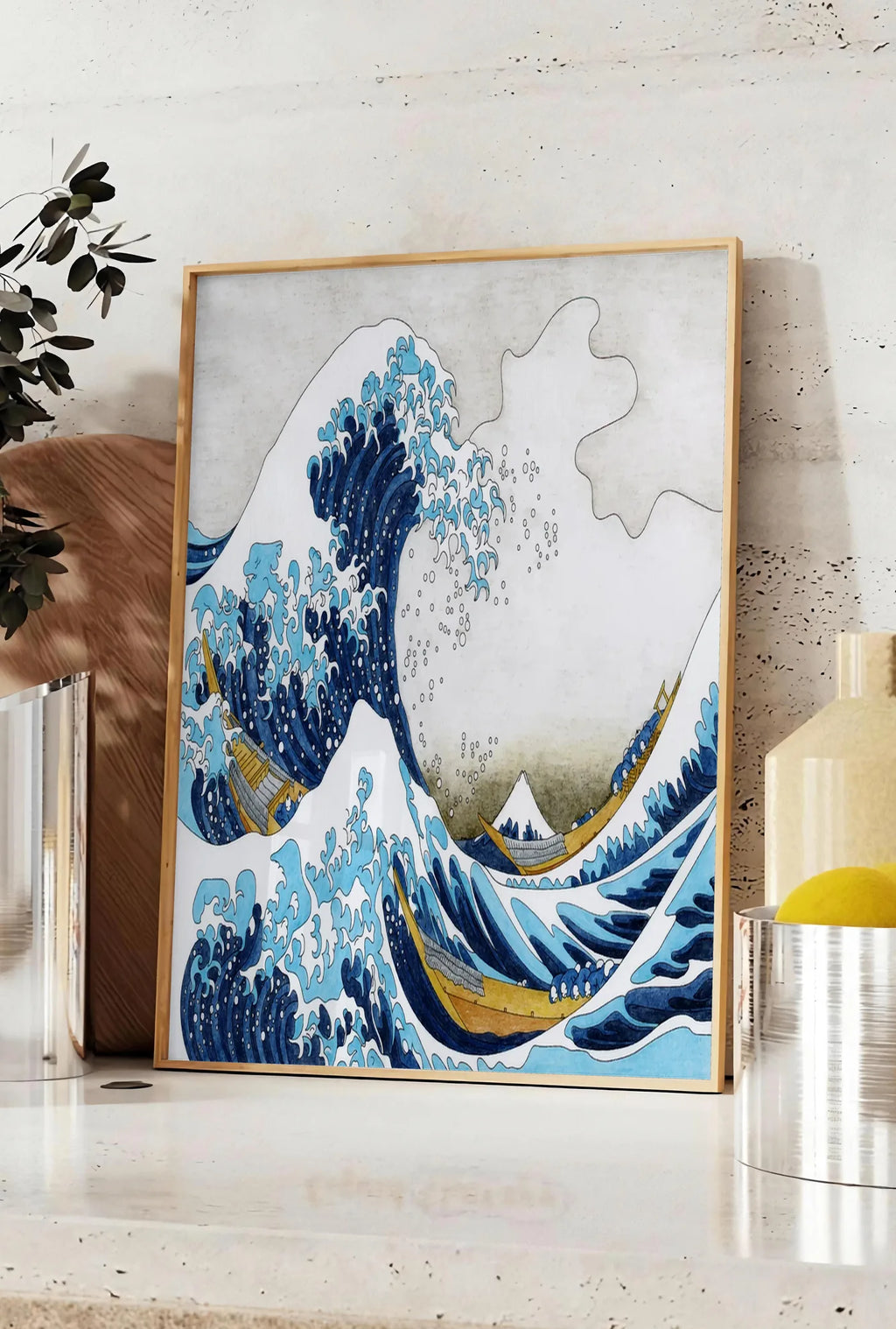 Affiche affiche Hokusai grande vague et barques de pecheurs, posee sur un plan de travail de cuisine en pierre claire, entre une branche d'eucalyptus en vase et un bocal de citrons