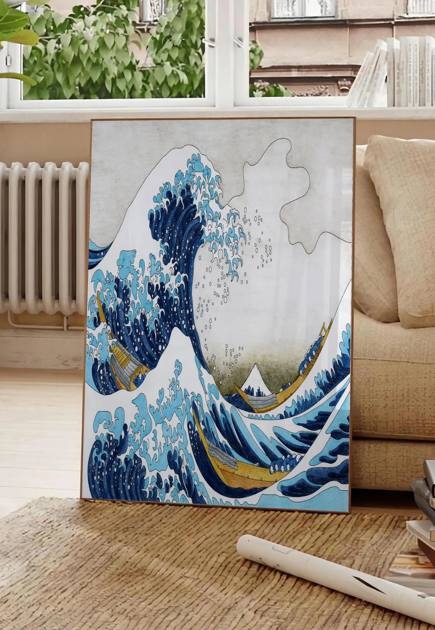 Poster affiche Hokusai grande vague et barques de pecheurs, posee au sol dans un salon parisien, devant une grande fenetre donnant sur un immeuble haussmannien, entre un ficus et un canape creme