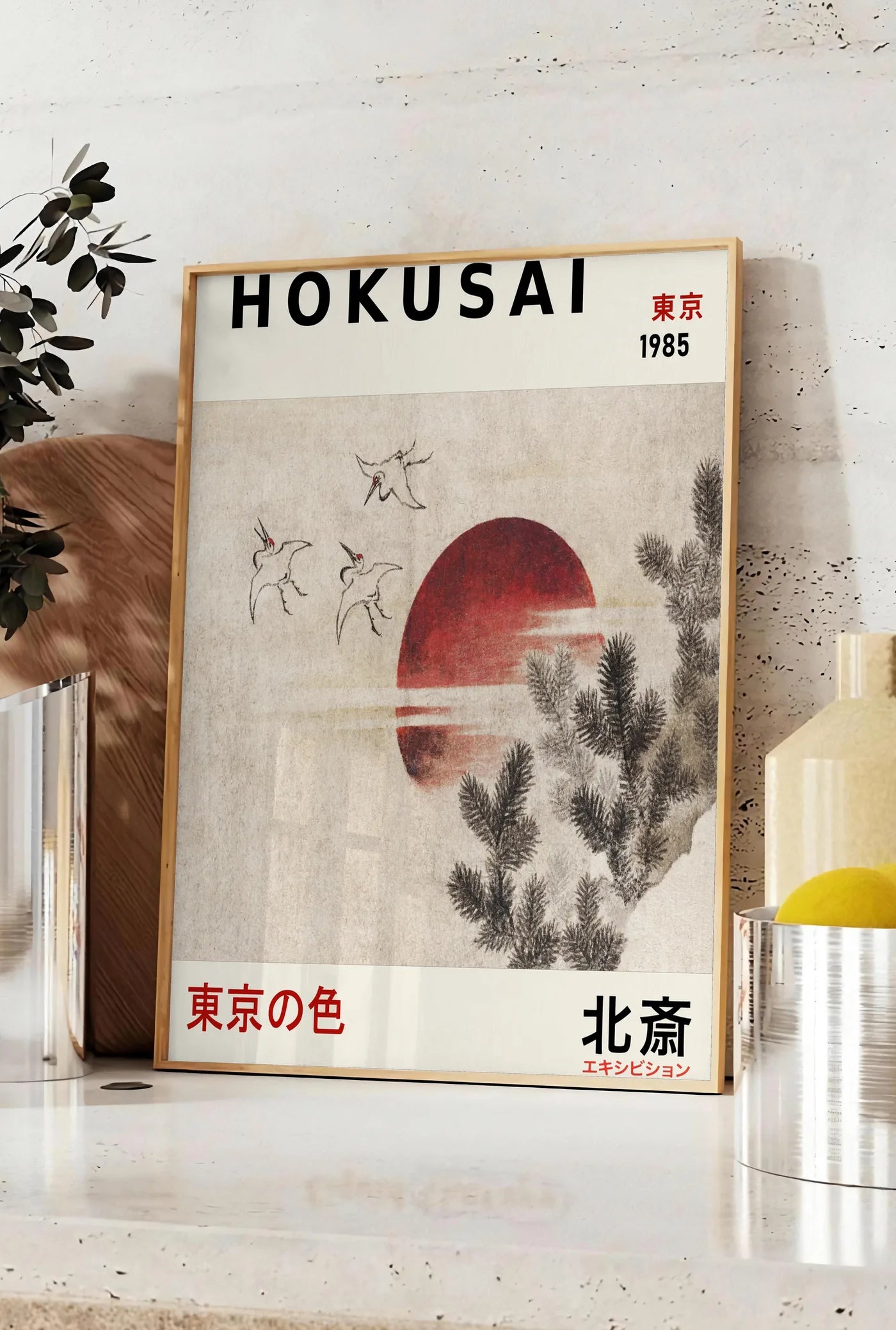 Affiche affiche Hokusai oiseaux en vol devant un soleil rouge, posee sur un plan de travail de cuisine en pierre claire, entre une branche d'eucalyptus en vase et un bocal de citrons