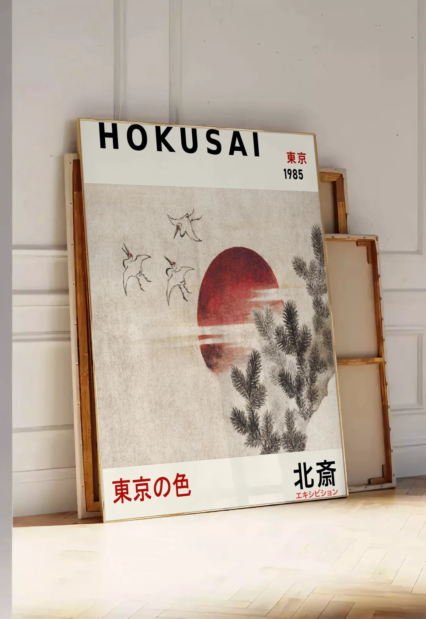 Tirage encadrable affiche Hokusai oiseaux en vol devant un soleil rouge, posee au sol dans une entree lumineuse, contre un mur a panneaux blancs, a cote de chassis en bois empiles
