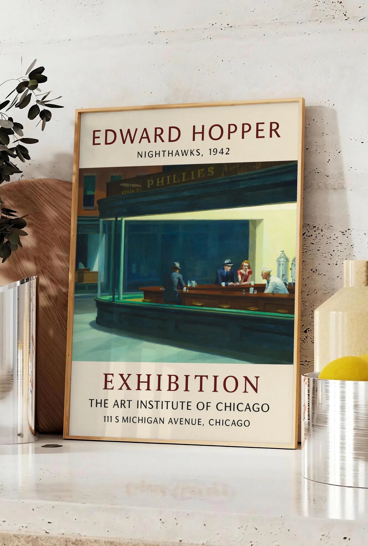 Affiche affiche Hopper Nighthawks, posee sur un plan de travail de cuisine en pierre claire, entre une branche d'eucalyptus en vase et un bocal de citrons