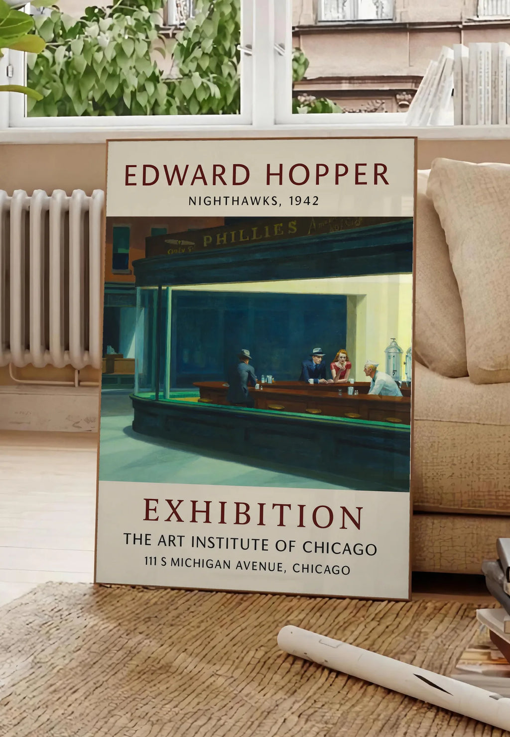 Poster affiche Hopper Nighthawks, posee au sol dans un salon parisien, devant une grande fenetre donnant sur un immeuble haussmannien, entre un ficus et un canape creme