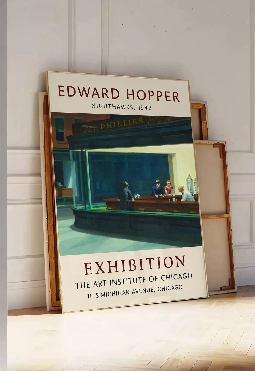 Tirage encadrable affiche Hopper Nighthawks, posee au sol dans une entree lumineuse, contre un mur a panneaux blancs, a cote de chassis en bois empiles