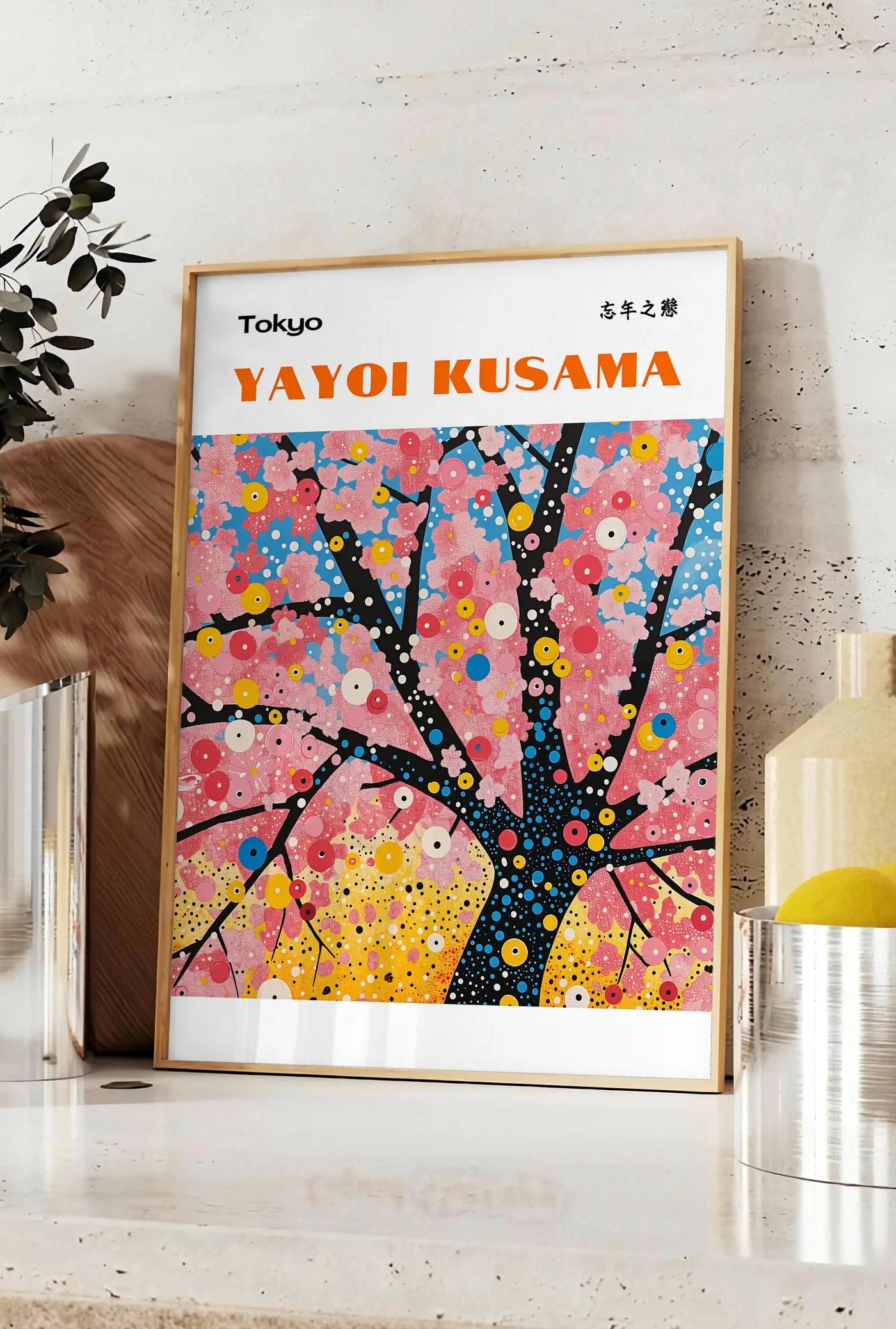 Affiche affiche cerisier a pois de Kusama art japonais, posee sur un plan de travail de cuisine en pierre claire, entre une branche d'eucalyptus en vase et un bocal de citrons