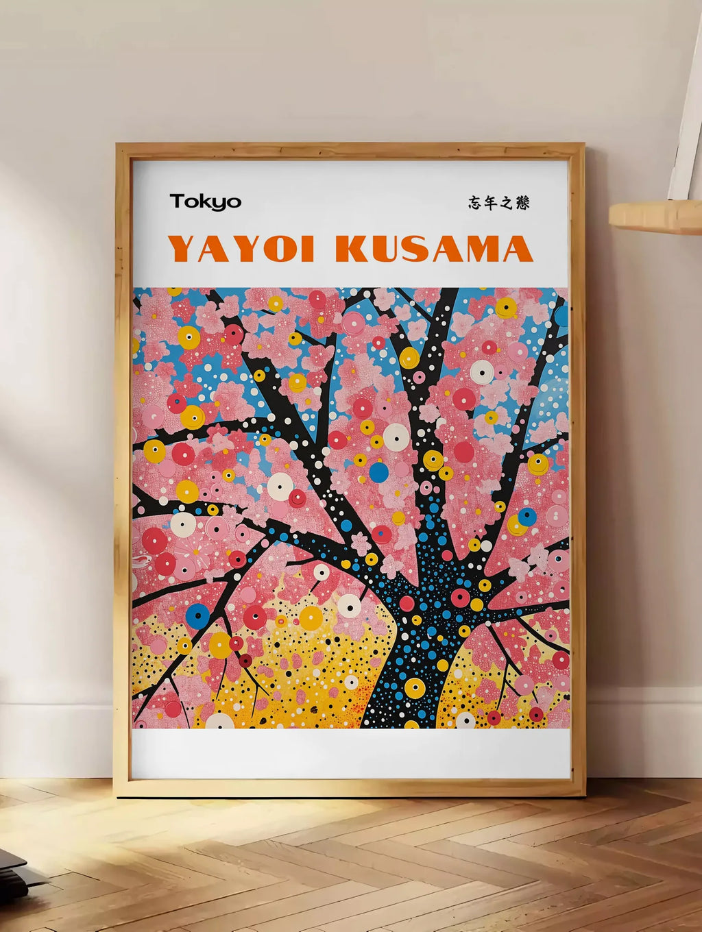 Estampe affiche cerisier a pois de Kusama art japonais, posee au sol dans un coin salon, sur un parquet a chevrons, pres d'une table d'appoint en chene chargee de livres