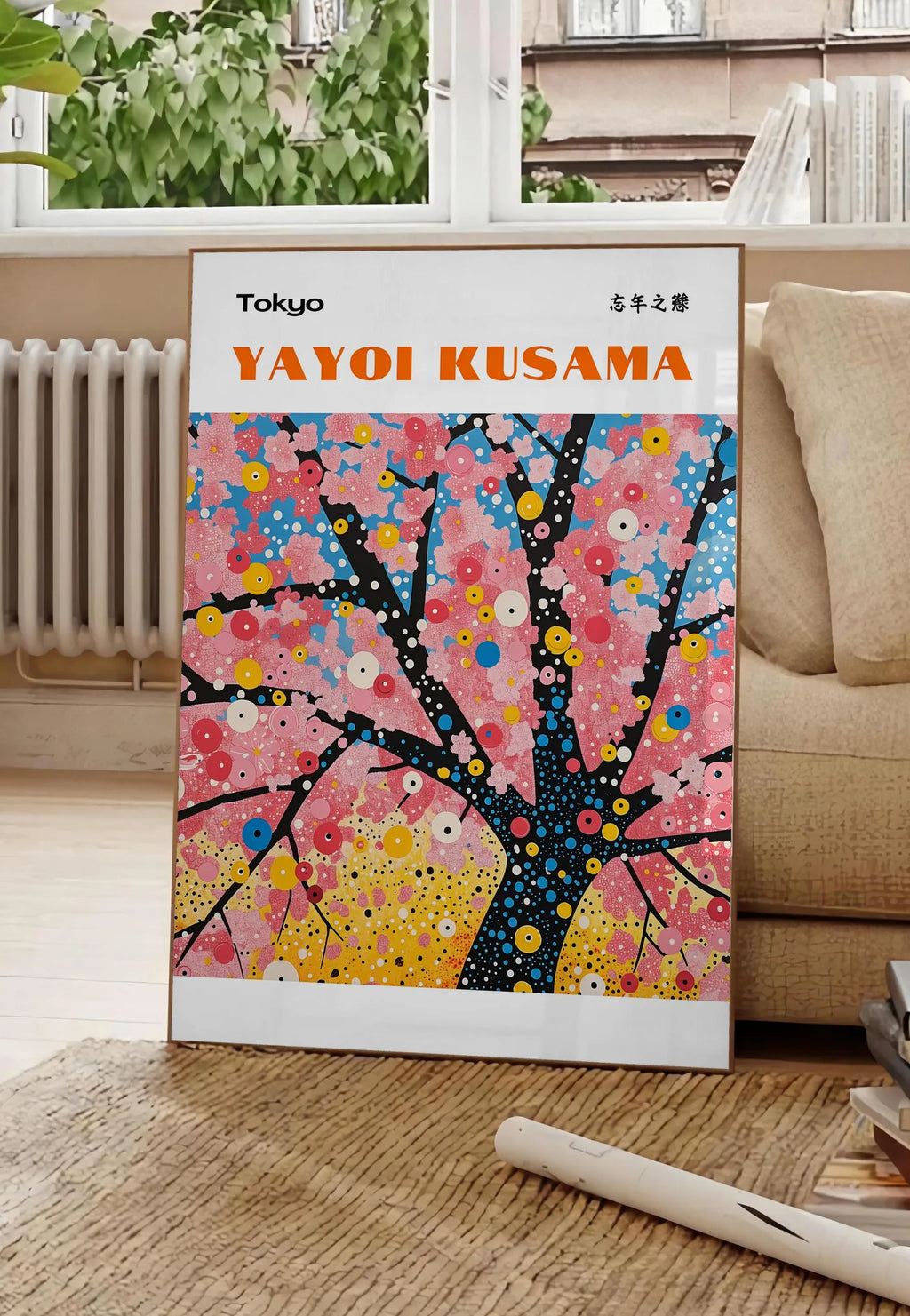 Poster affiche cerisier a pois de Kusama art japonais, posee au sol dans un salon parisien, devant une grande fenetre donnant sur un immeuble haussmannien, entre un ficus et un canape creme