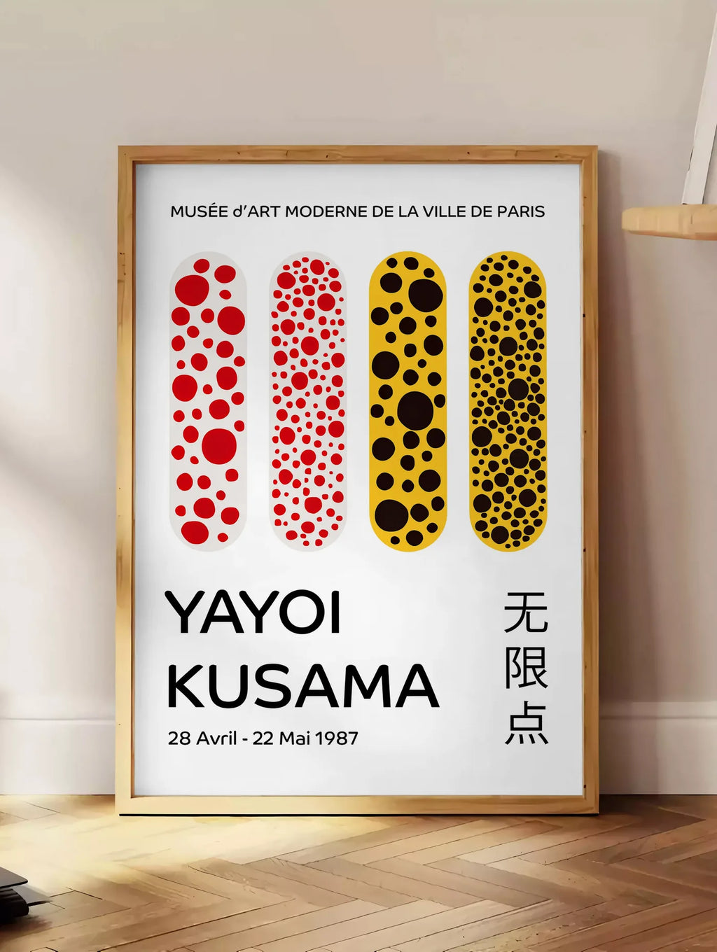 Estampe affiche capsules a pois de Kusama art japonais, posee au sol dans un coin salon, sur un parquet a chevrons, pres d'une table d'appoint en chene chargee de livres