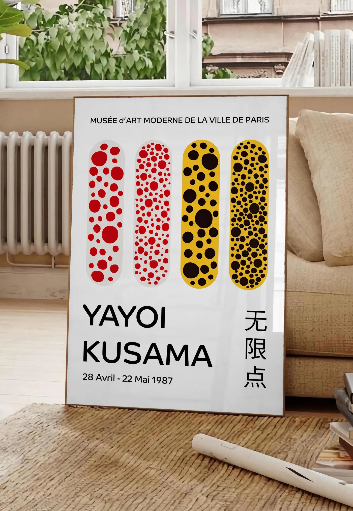 Poster affiche capsules a pois de Kusama art japonais, posee au sol dans un salon parisien, devant une grande fenetre donnant sur un immeuble haussmannien, entre un ficus et un canape creme