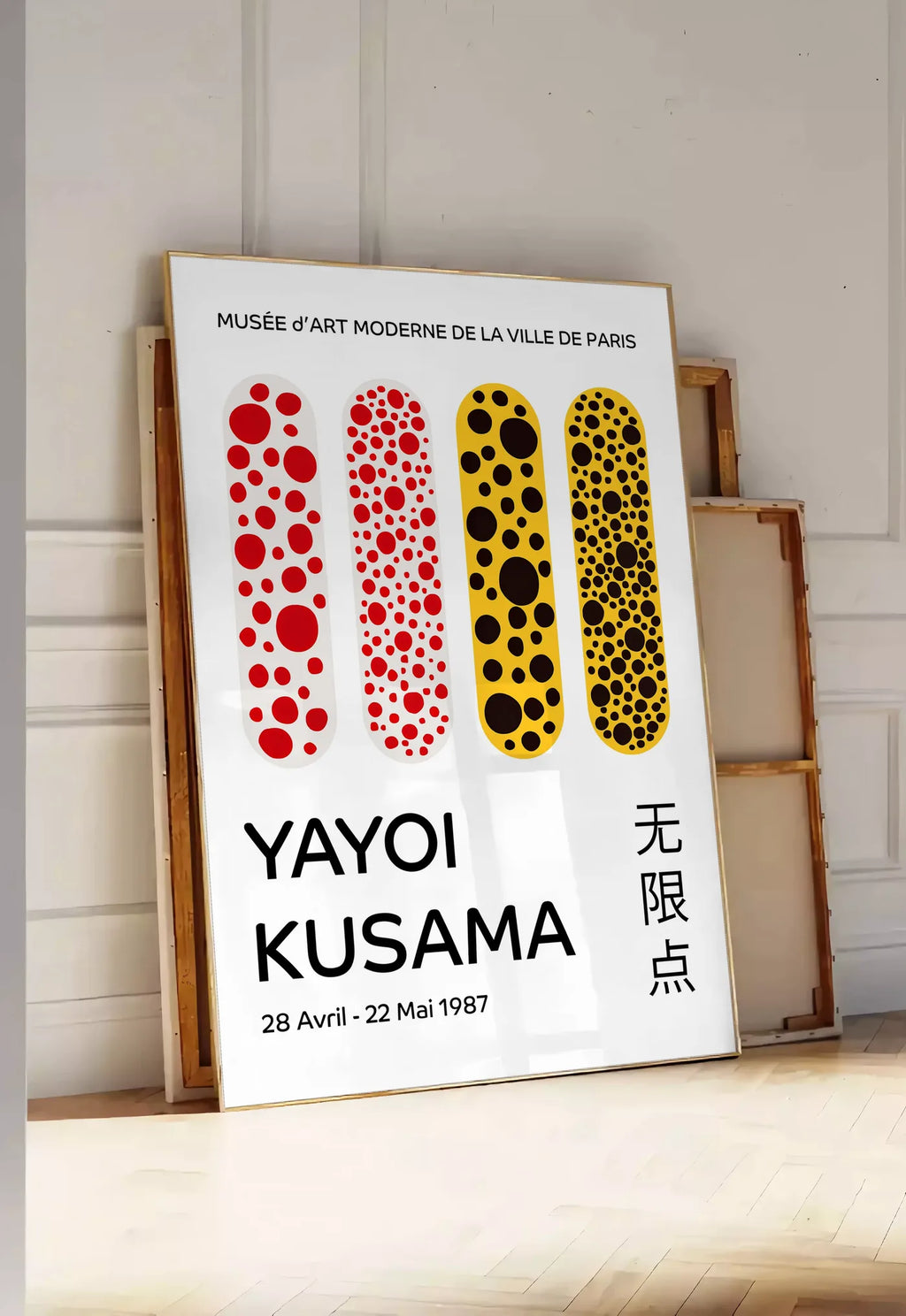 Tirage encadrable affiche capsules a pois de Kusama art japonais, posee au sol dans une entree lumineuse, contre un mur a panneaux blancs, a cote de chassis en bois empiles