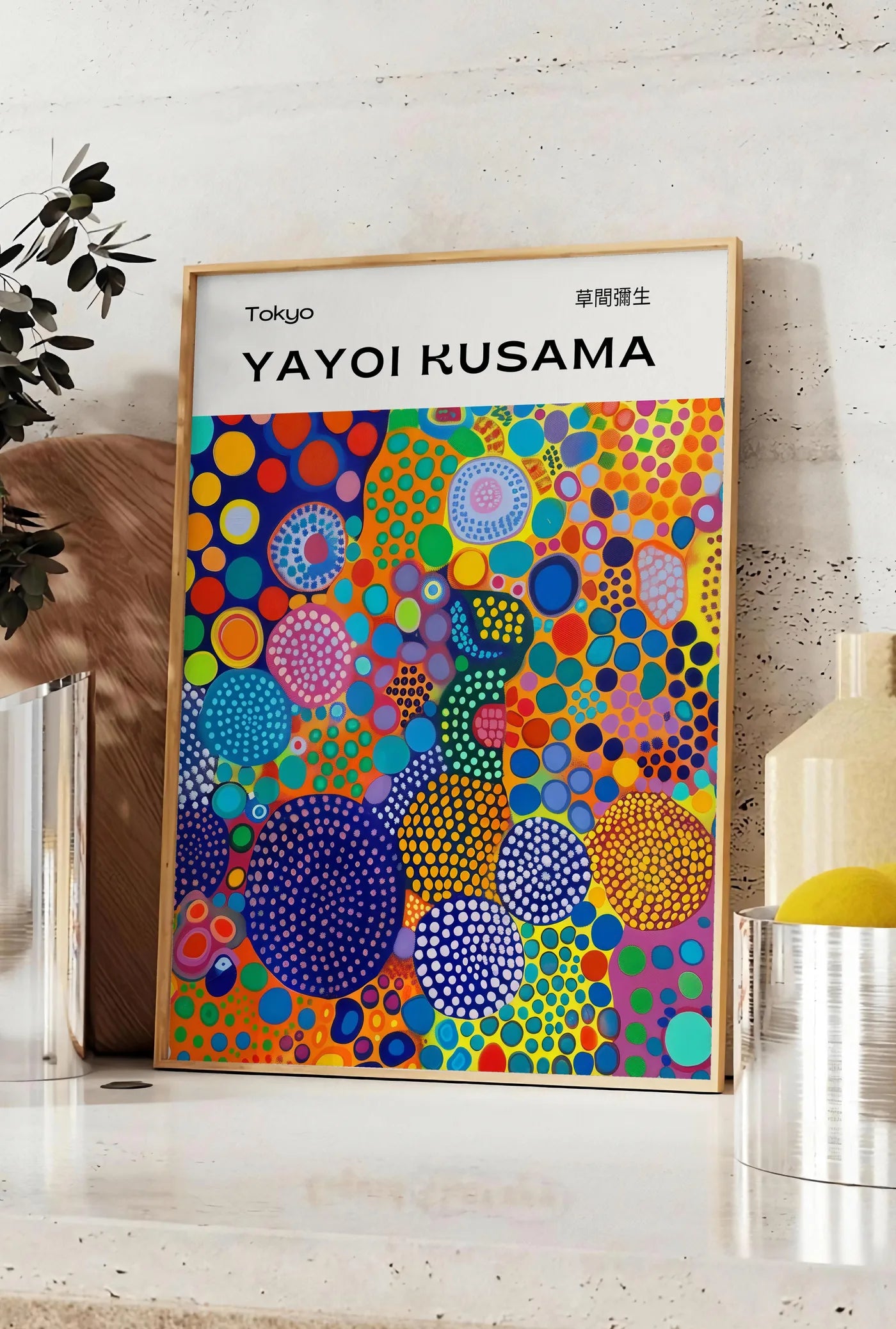 Affiche affiche cercles multicolores de Kusama art japonais, posee sur un plan de travail de cuisine en pierre claire, entre une branche d'eucalyptus en vase et un bocal de citrons