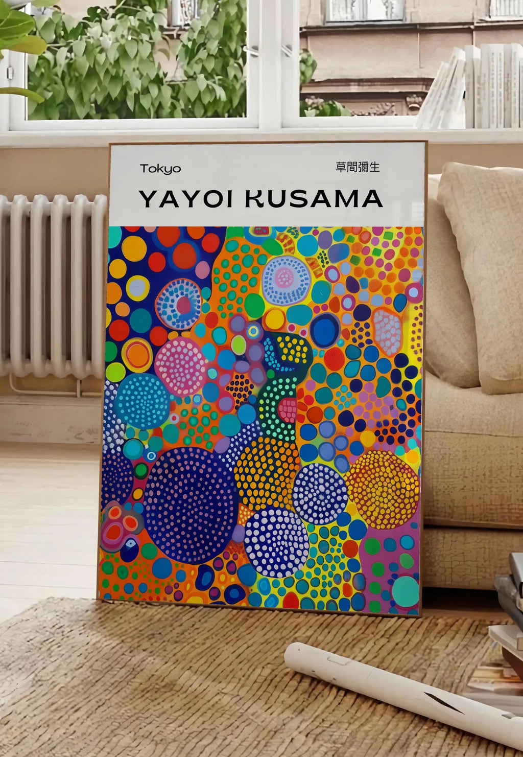 Poster affiche cercles multicolores de Kusama art japonais, posee au sol dans un salon parisien, devant une grande fenetre donnant sur un immeuble haussmannien, entre un ficus et un canape creme