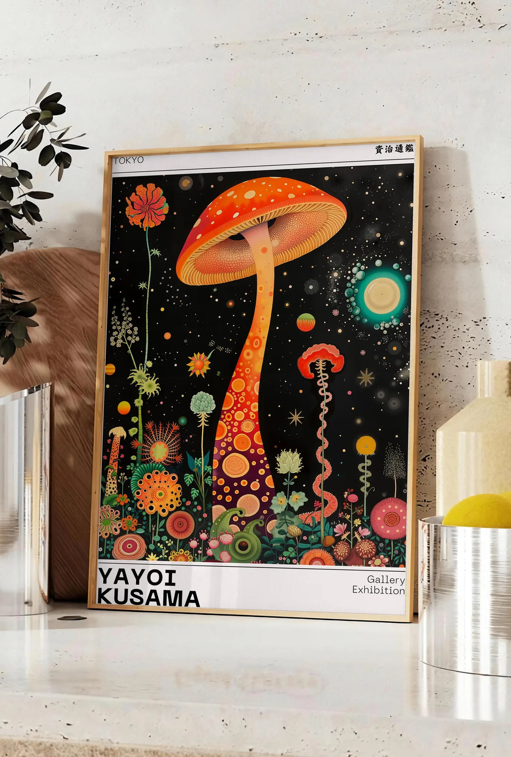 Affiche affiche champignon orange de Kusama art japonais, posee sur un plan de travail de cuisine en pierre claire, entre une branche d'eucalyptus en vase et un bocal de citrons