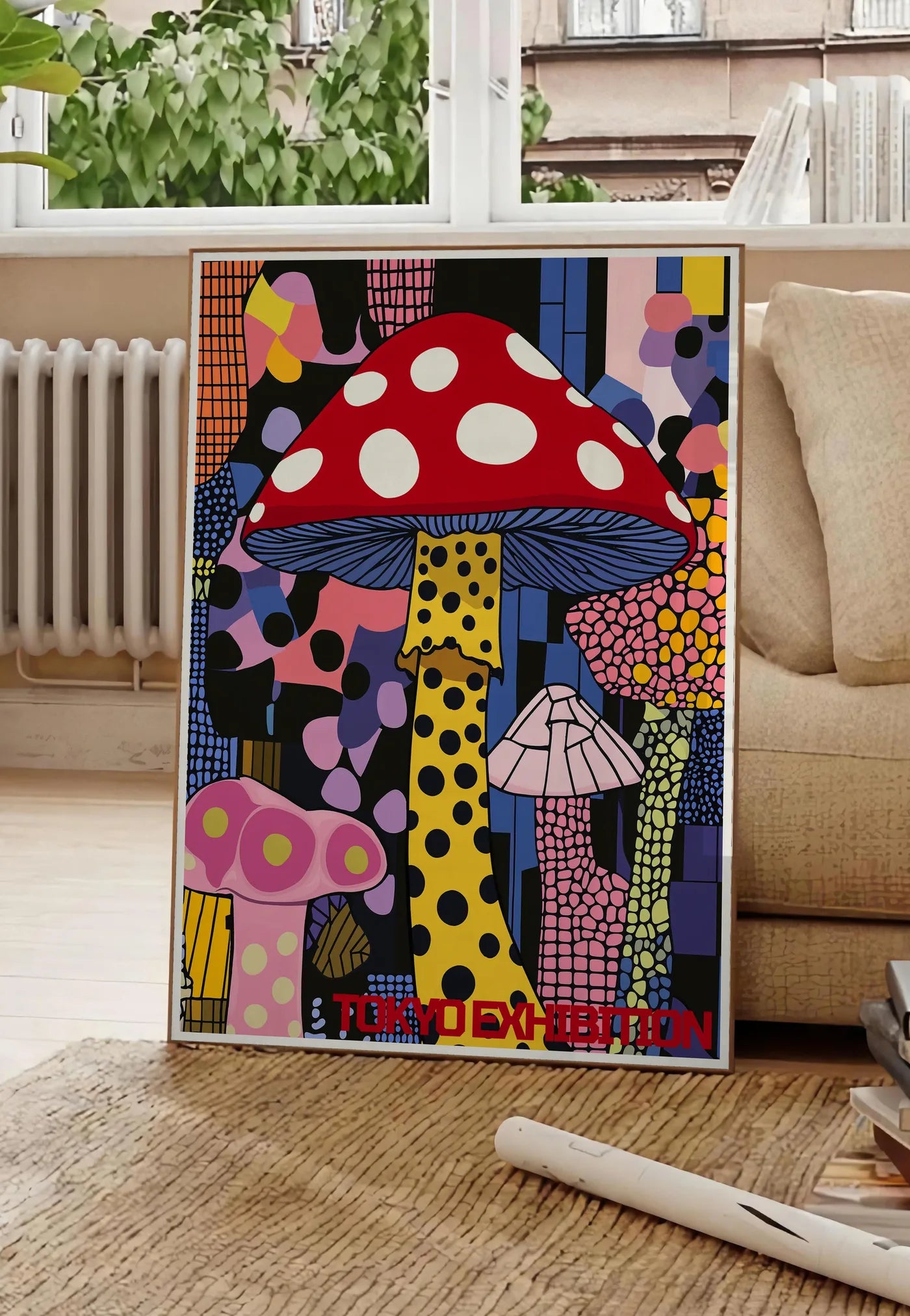 Poster affiche champignon pop de Kusama art japonais, posee au sol dans un salon parisien, devant une grande fenetre donnant sur un immeuble haussmannien, entre un ficus et un canape creme
