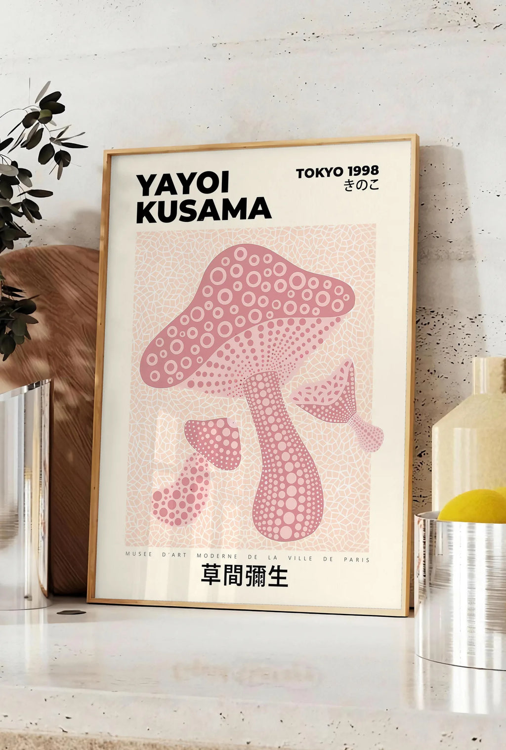 Affiche affiche champignon rose de Kusama art japonais, posee sur un plan de travail de cuisine en pierre claire, entre une branche d'eucalyptus en vase et un bocal de citrons