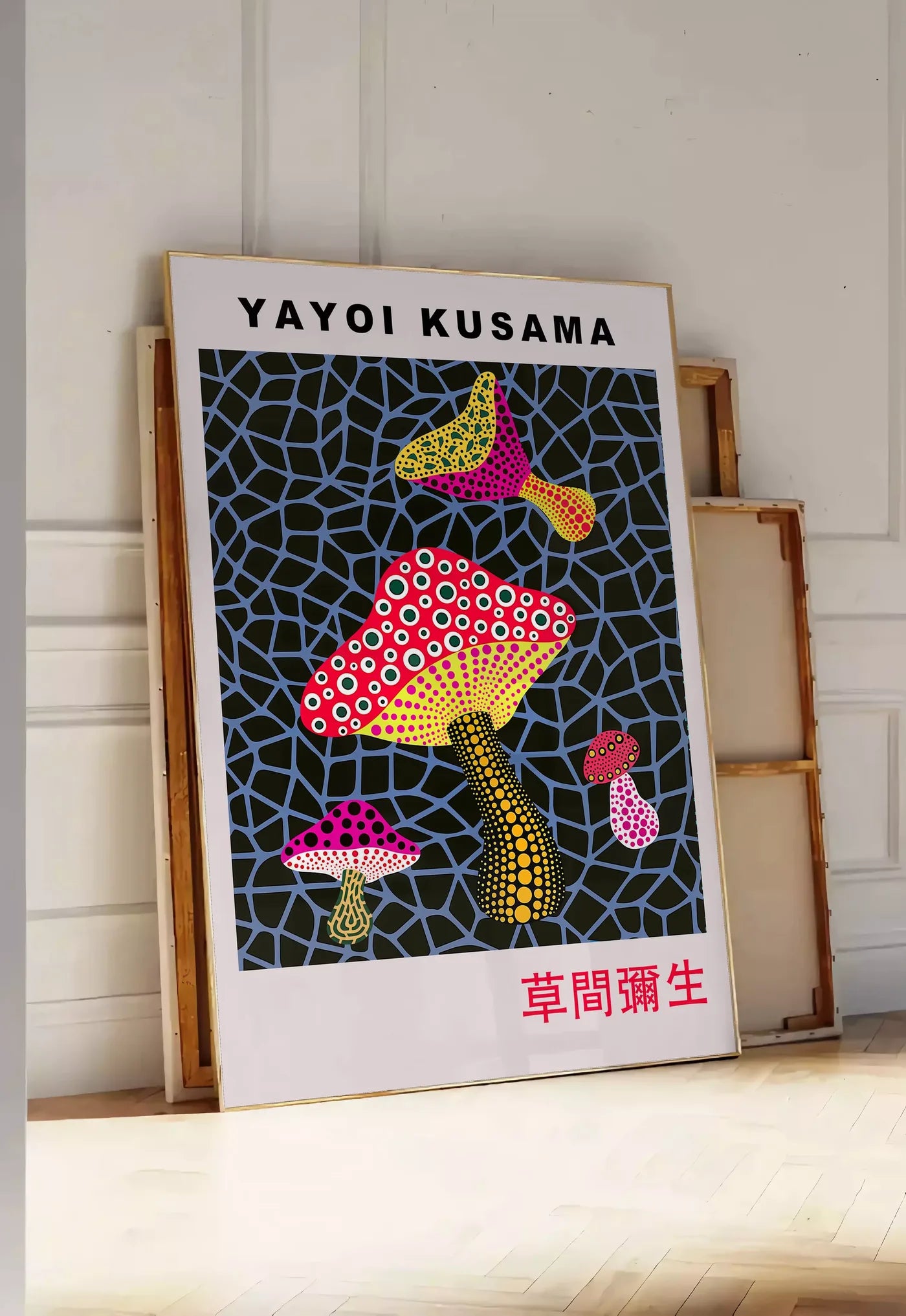 Tirage encadrable affiche champignons a pois de Kusama art japonais, posee au sol dans une entree lumineuse, contre un mur a panneaux blancs, a cote de chassis en bois empiles