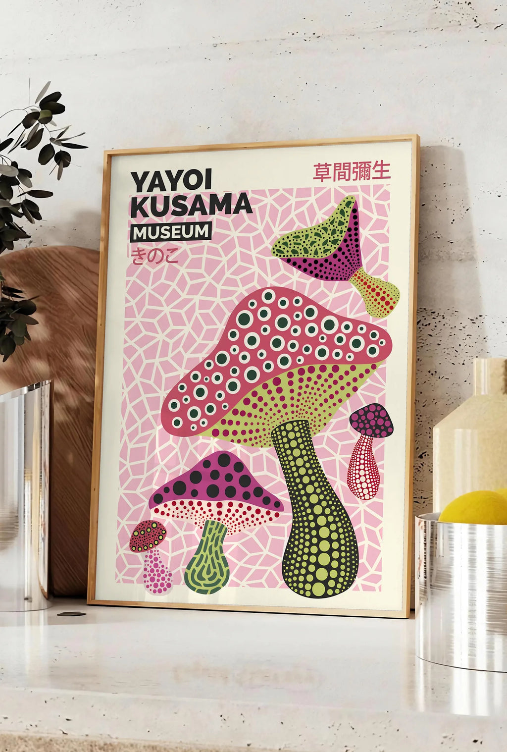 Affiche affiche champignons multicolores de Kusama art japonais, posee sur un plan de travail de cuisine en pierre claire, entre une branche d'eucalyptus en vase et un bocal de citrons