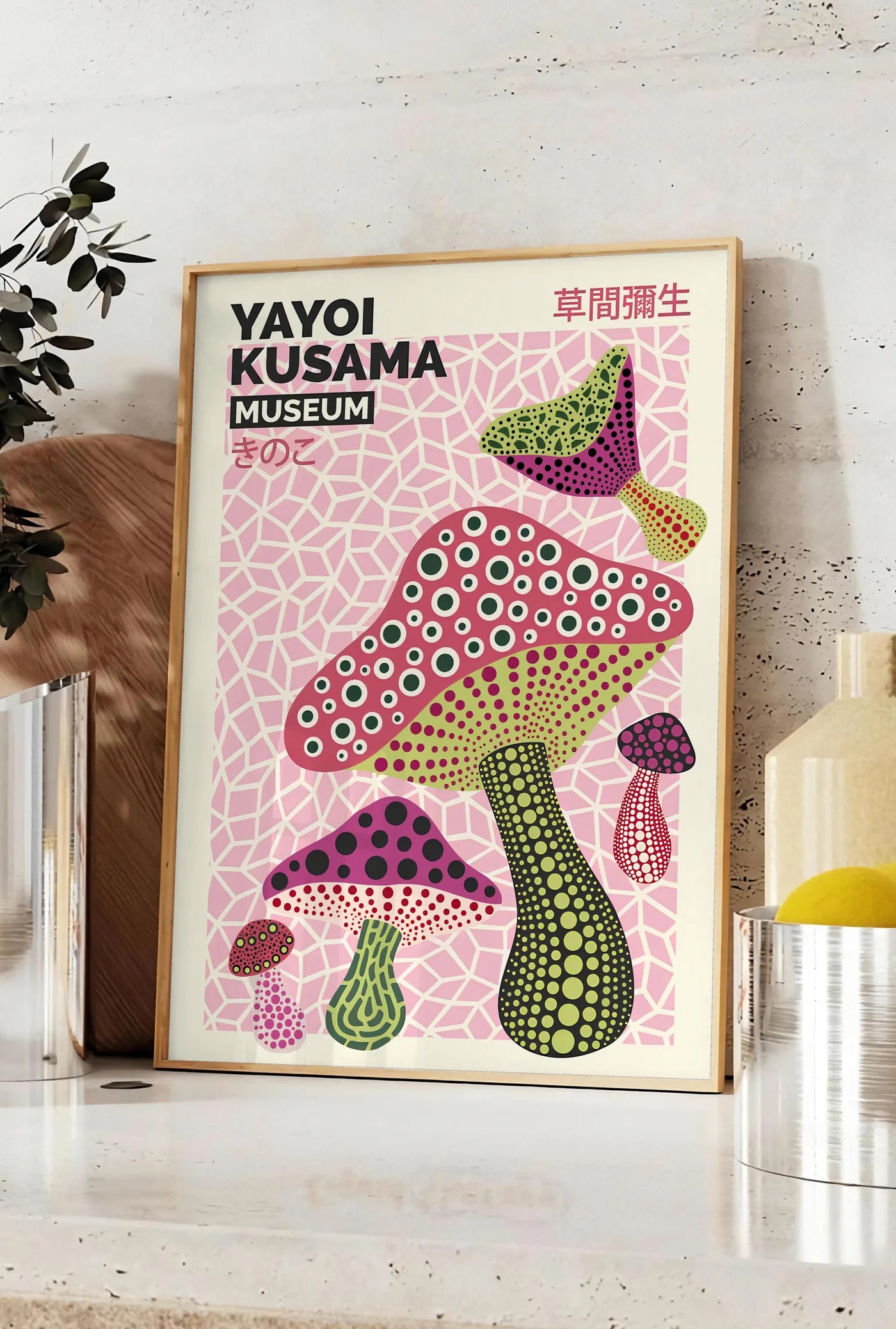 Affiche affiche champignons multicolores de Kusama art japonais, posee sur un plan de travail de cuisine en pierre claire, entre une branche d'eucalyptus en vase et un bocal de citrons