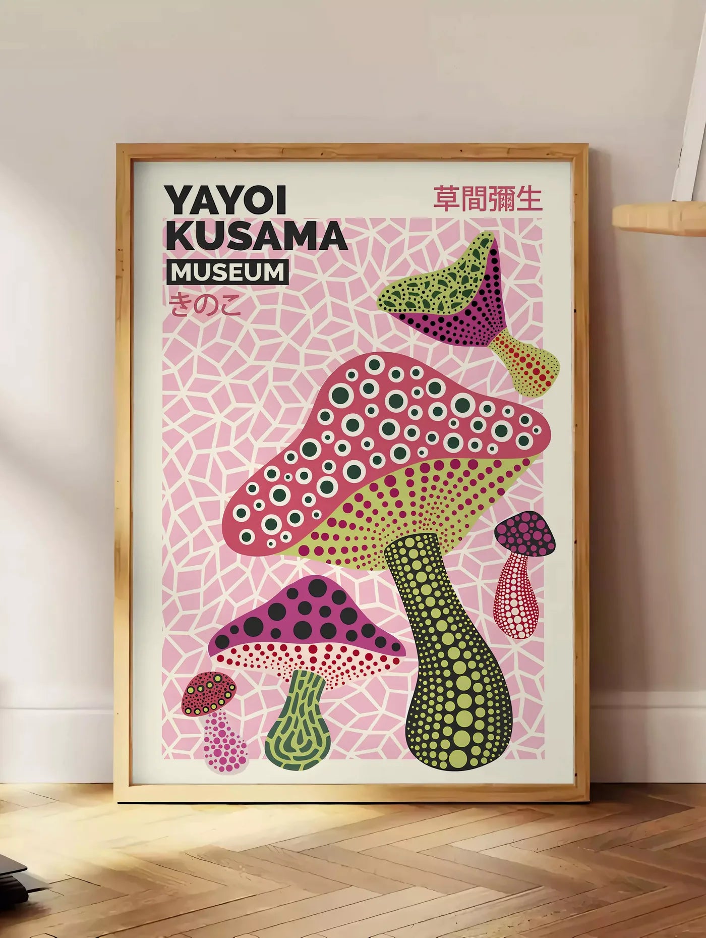 Estampe affiche champignons multicolores de Kusama art japonais, posee au sol dans un coin salon, sur un parquet a chevrons, pres d'une table d'appoint en chene chargee de livres