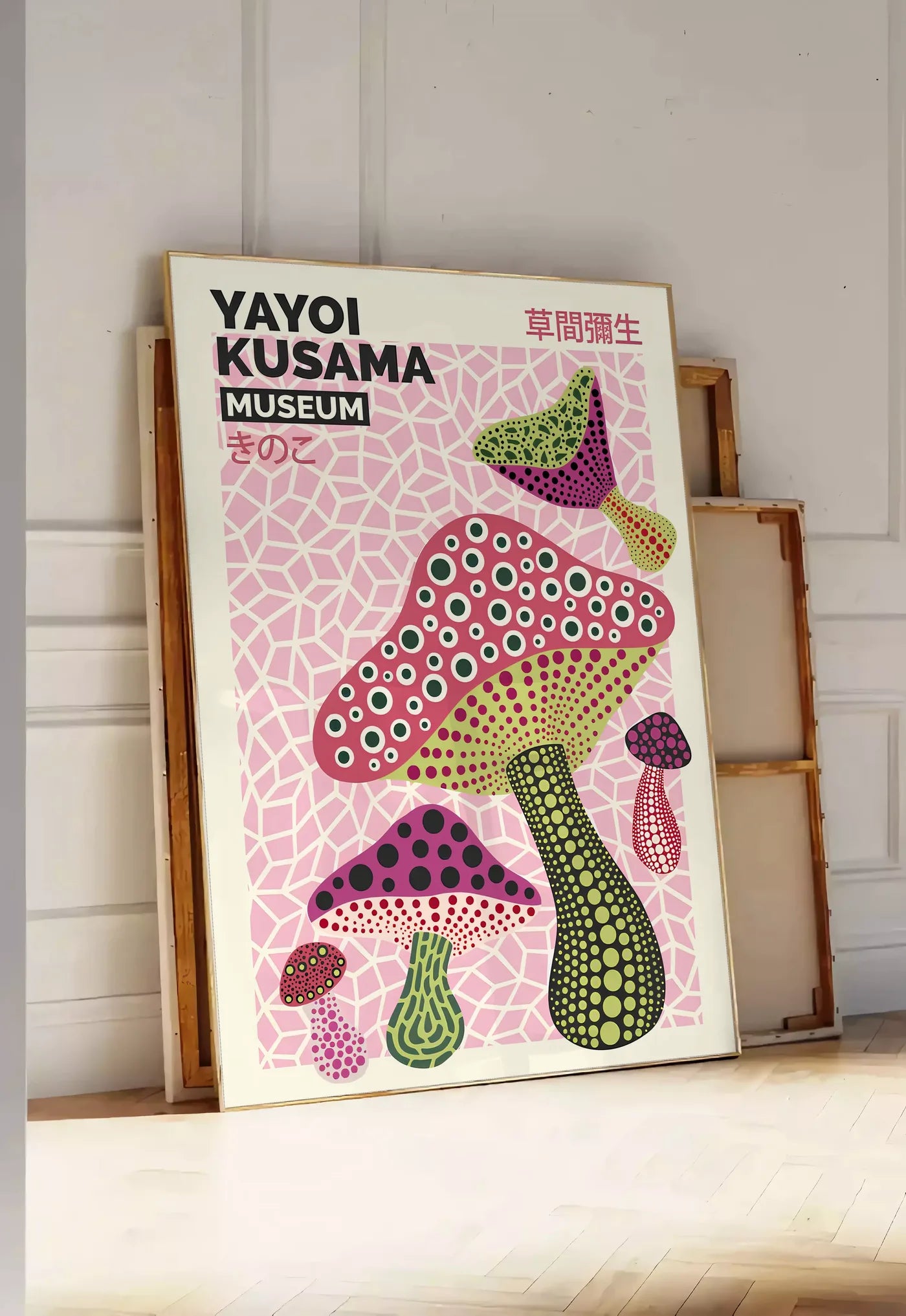 Tirage encadrable affiche champignons multicolores de Kusama art japonais, posee au sol dans une entree lumineuse, contre un mur a panneaux blancs, a cote de chassis en bois empiles