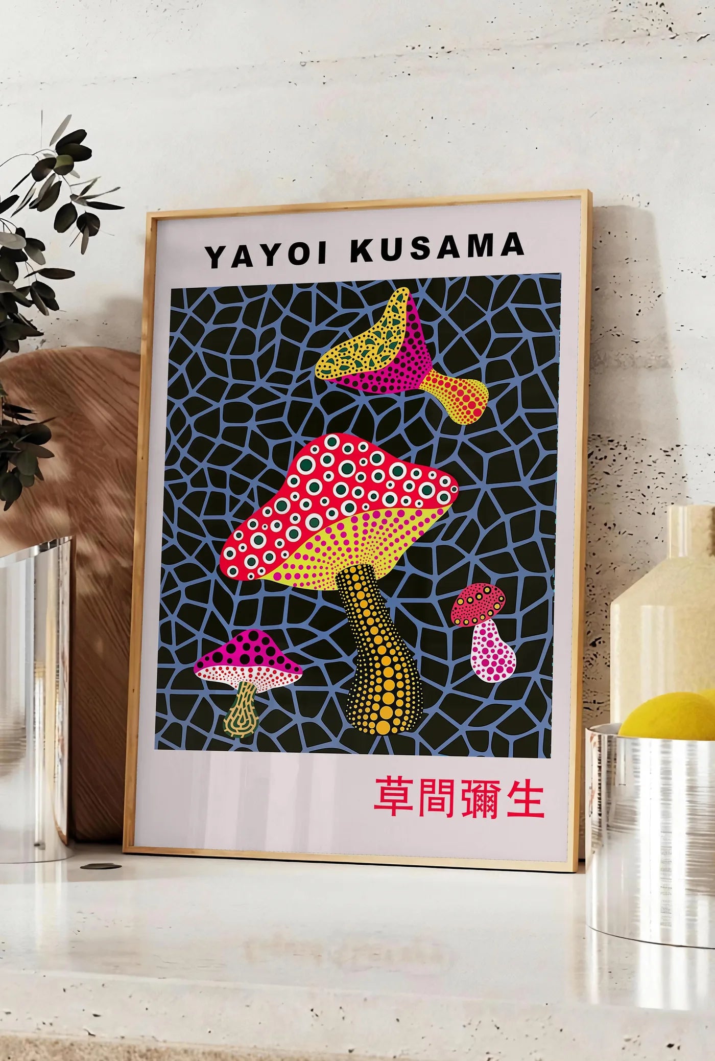 Affiche affiche champignons a pois de Kusama art japonais, posee sur un plan de travail de cuisine en pierre claire, entre une branche d'eucalyptus en vase et un bocal de citrons