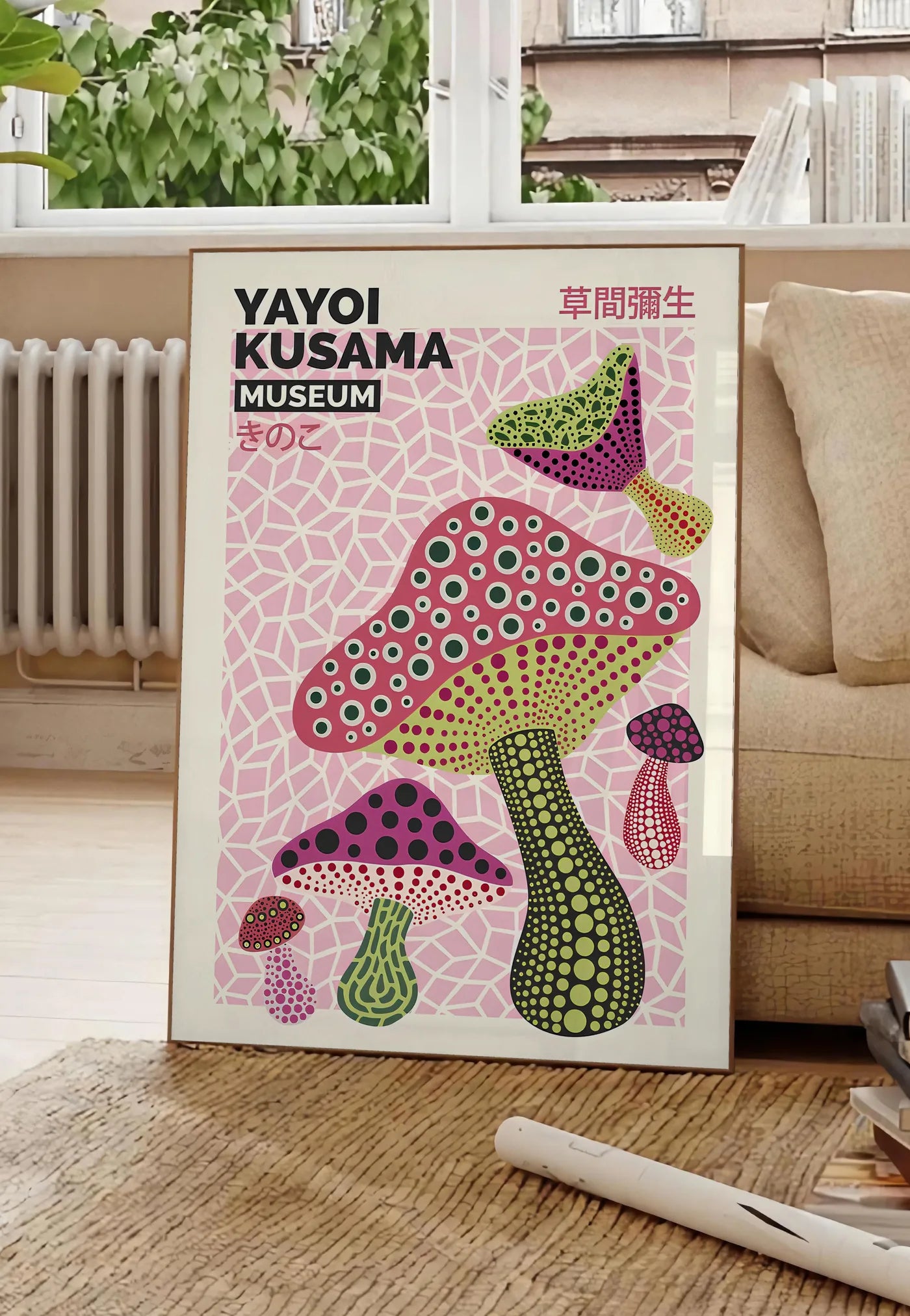 Poster affiche champignons magenta de Kusama art japonais, posee au sol dans un salon parisien, devant une grande fenetre donnant sur un immeuble haussmannien, entre un ficus et un canape creme