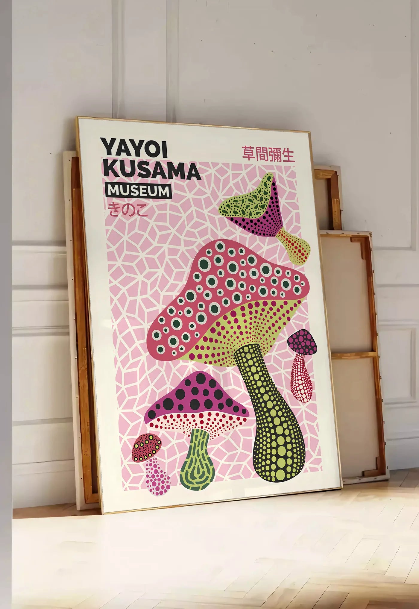 Tirage encadrable affiche champignons magenta de Kusama art japonais, posee au sol dans une entree lumineuse, contre un mur a panneaux blancs, a cote de chassis en bois empiles