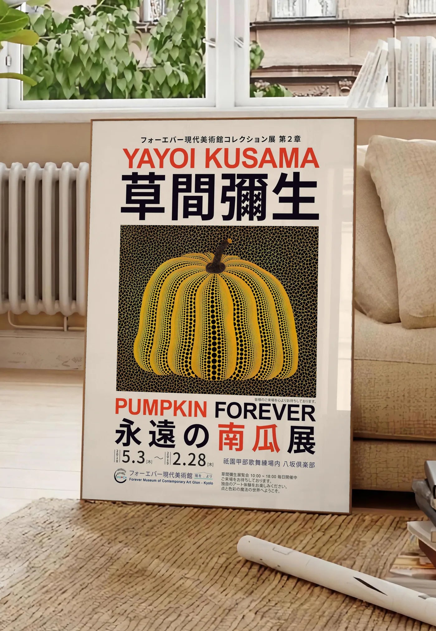 Poster affiche Kusama citrouille jaune a pois sur fond noir en affiche d exposition, posee au sol dans un salon parisien, devant une grande fenetre donnant sur un immeuble haussmannien, entre un ficus et un canape creme