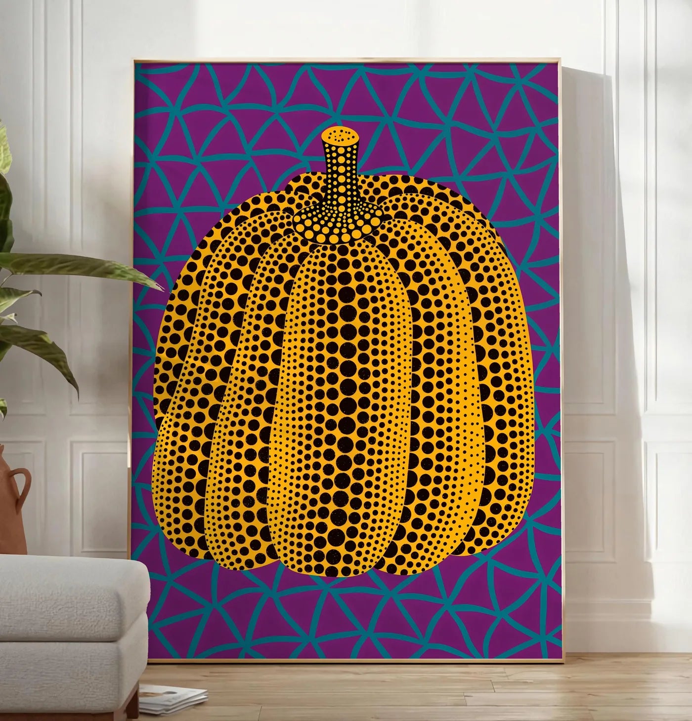 Reproduction affiche Kusama citrouille jaune a pois sur fond violet a filet bleu, posee au sol dans un salon minimaliste clair, a cote d'un canape beige et d'une plante verte, sur un parquet clair